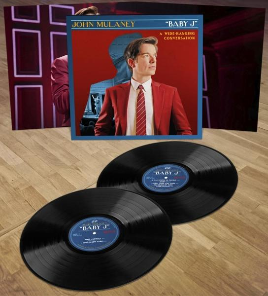 John Mulaney "Baby J" Vinyl-Cover und zwei LPs auf Holzboden.