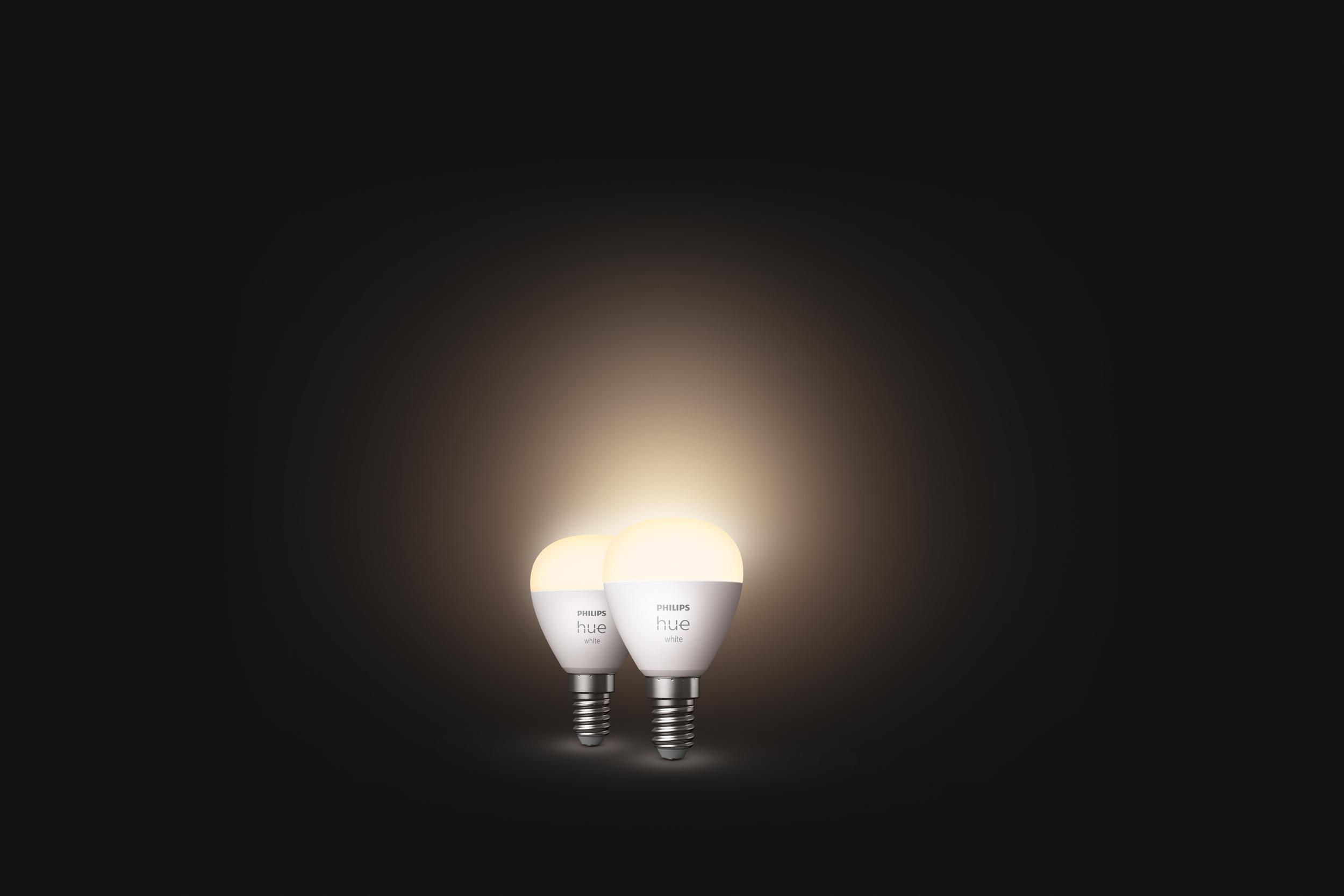 Zwei weiße Hue Smart-Glühbirnen leuchten. Dunkler Hintergrund.