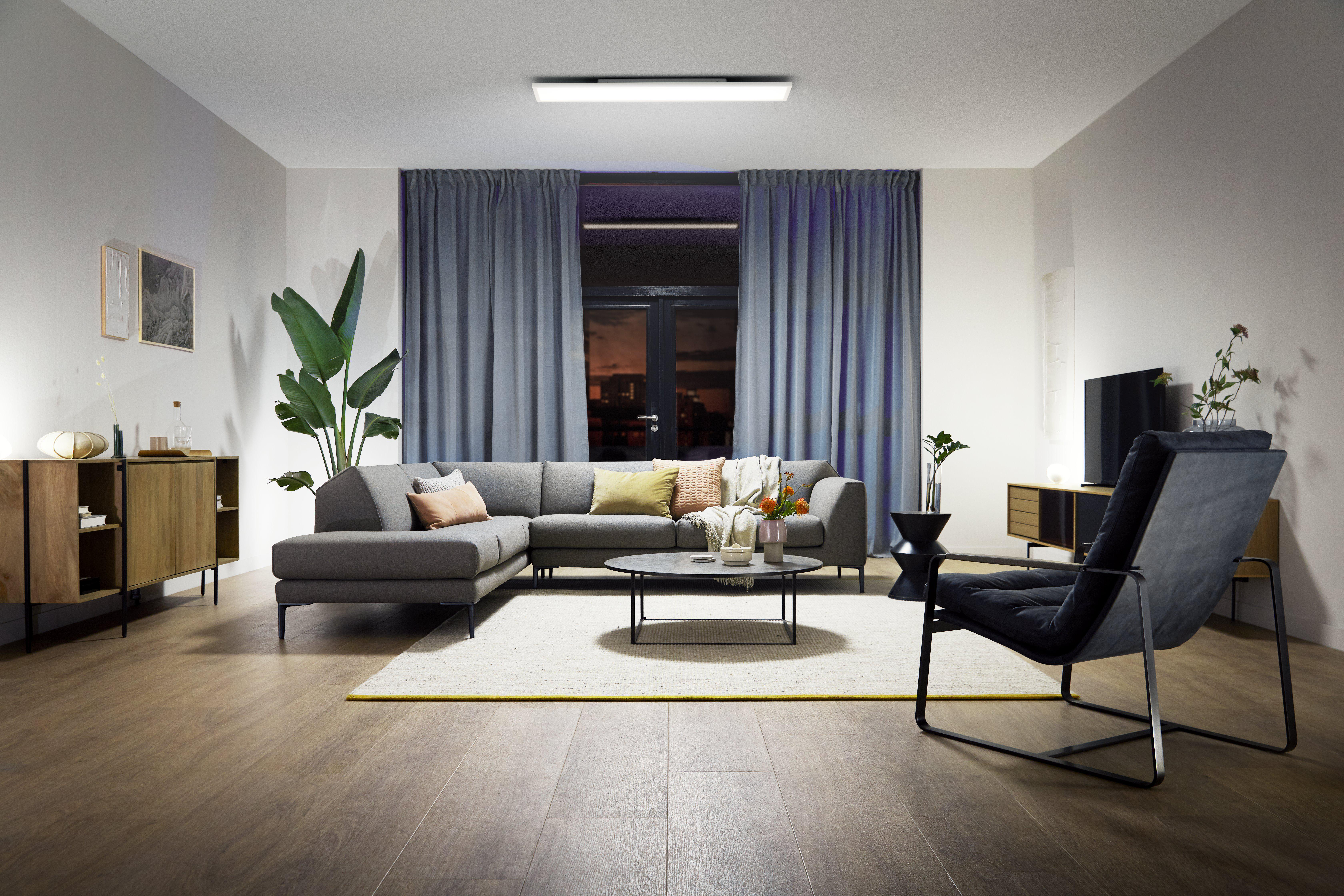 Modernes Wohnzimmer mit grauem Sofa, großem Fenster, Stuhl, Couchtisch, Holzschrank und Pflanze.