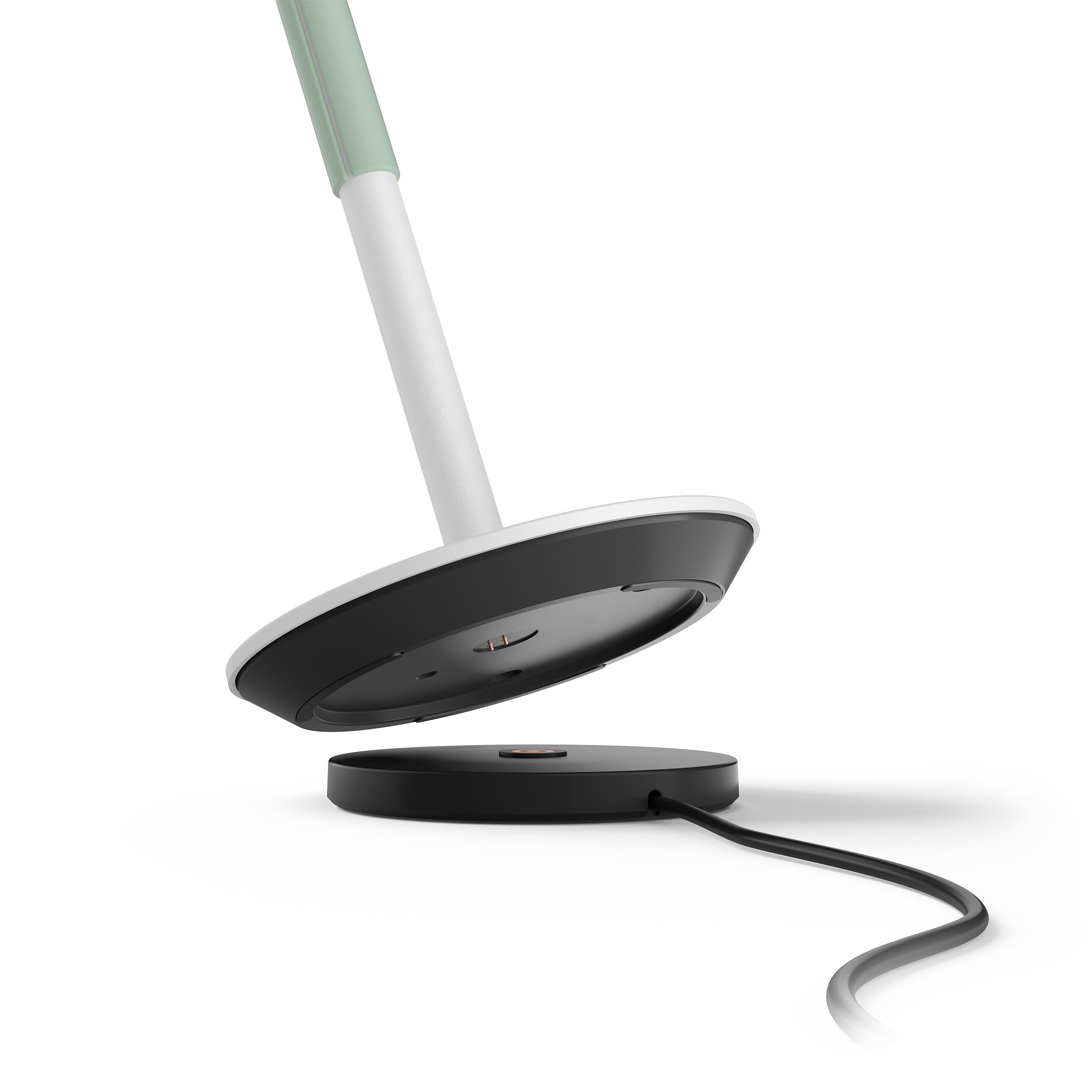 Eine weiß-grüne Schreibtischlampe auf einer schwarzen Ladestation mit Ladekabel.