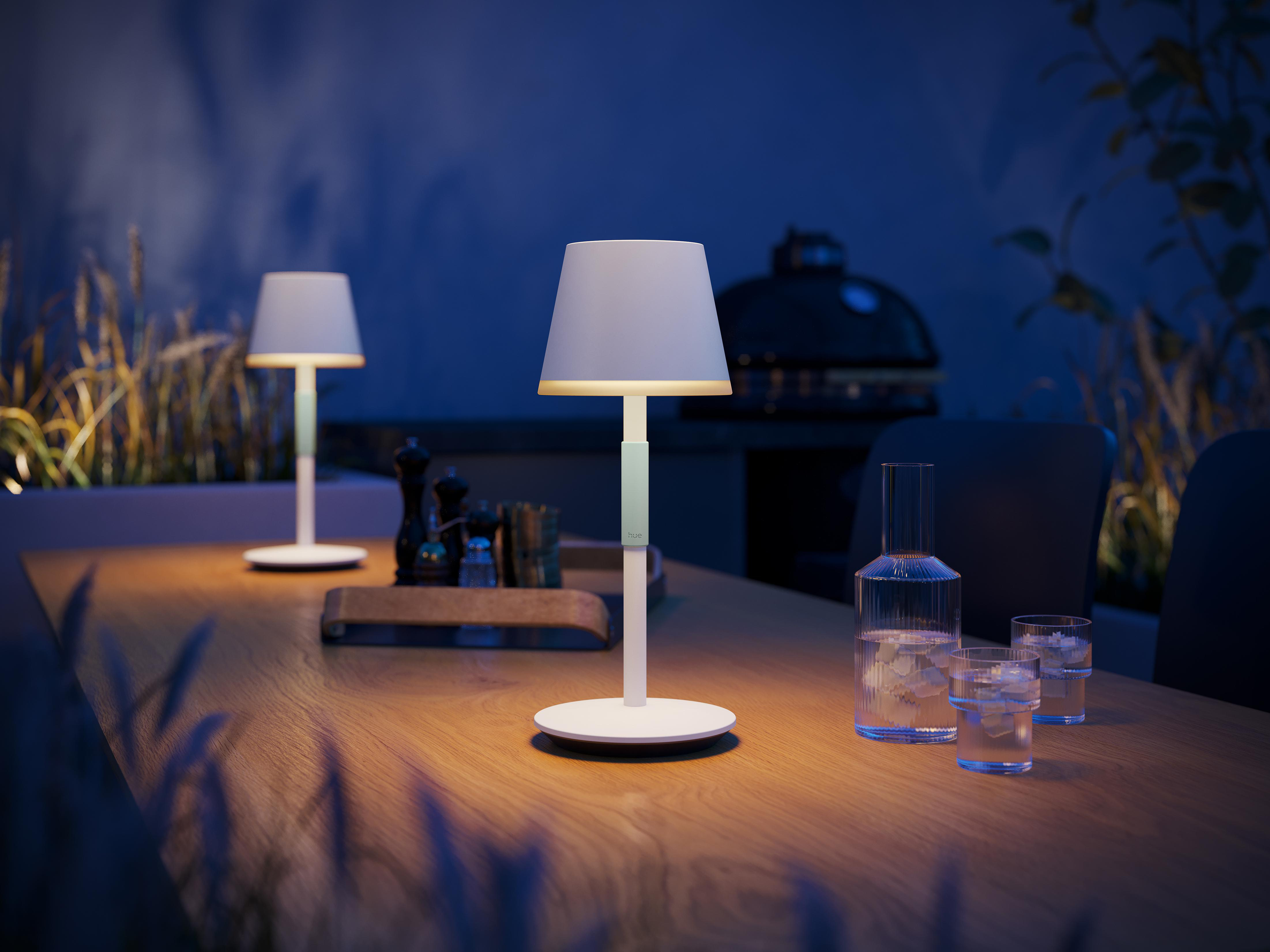 Zwei weiße Lampen auf einem Holztisch bei Nacht, verschwommener Hintergrund.