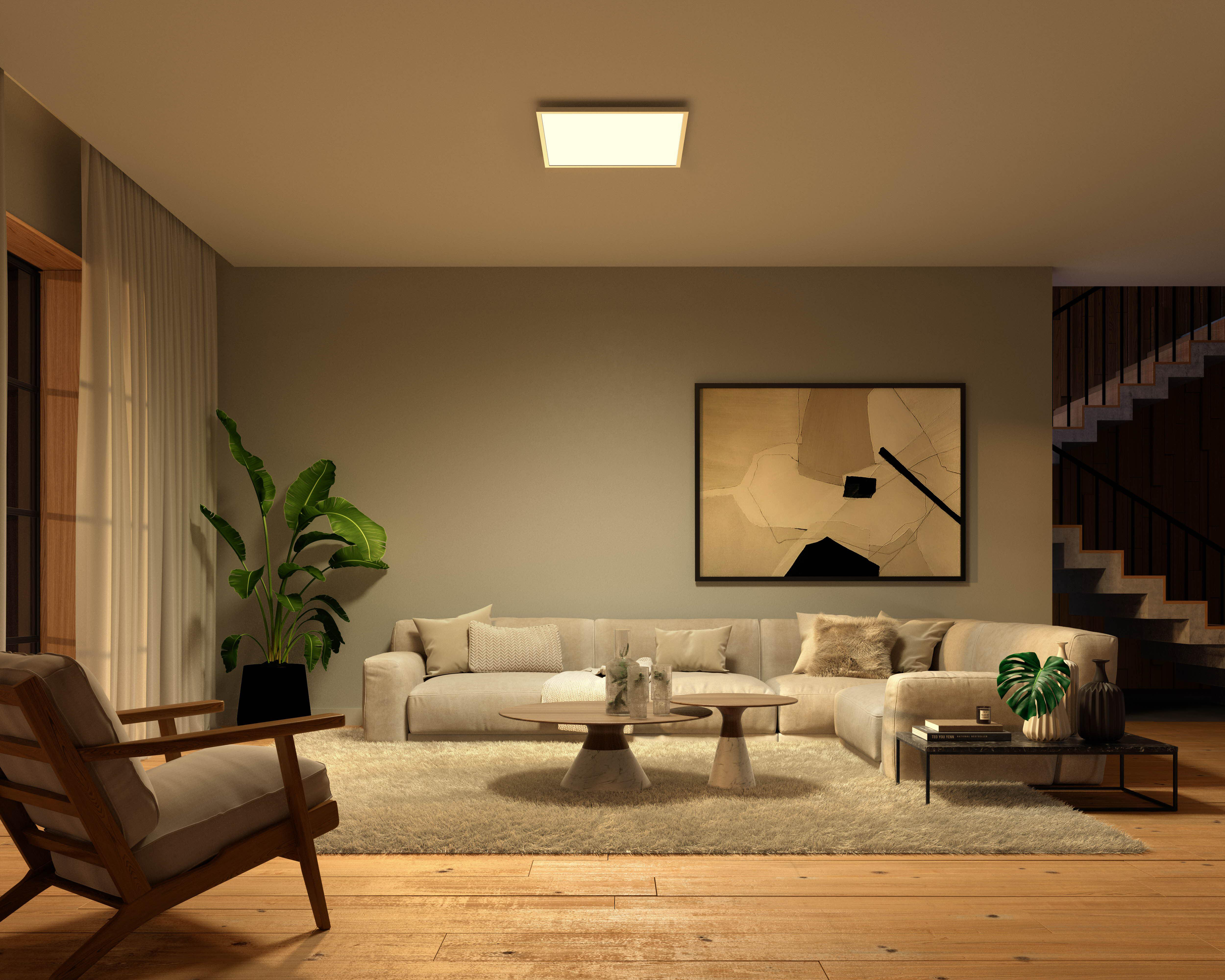 Wohnzimmer mit großem Sofa, Holzboden, Pflanzen und quadratischer Deckenleuchte.