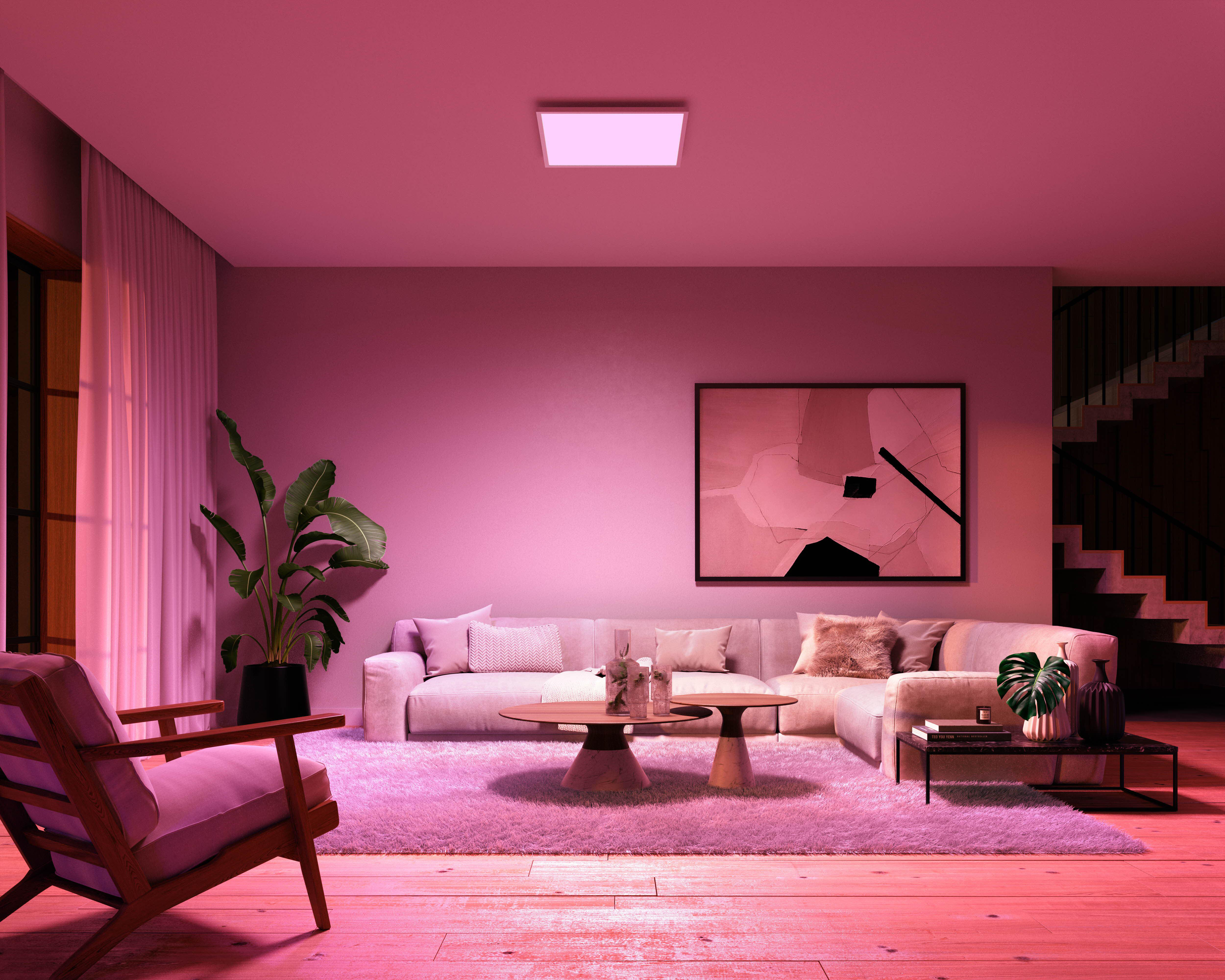 Ein Wohnzimmer mit rosa Farbton, Sofa, Teppich und einem Lichtpaneel an der Decke.