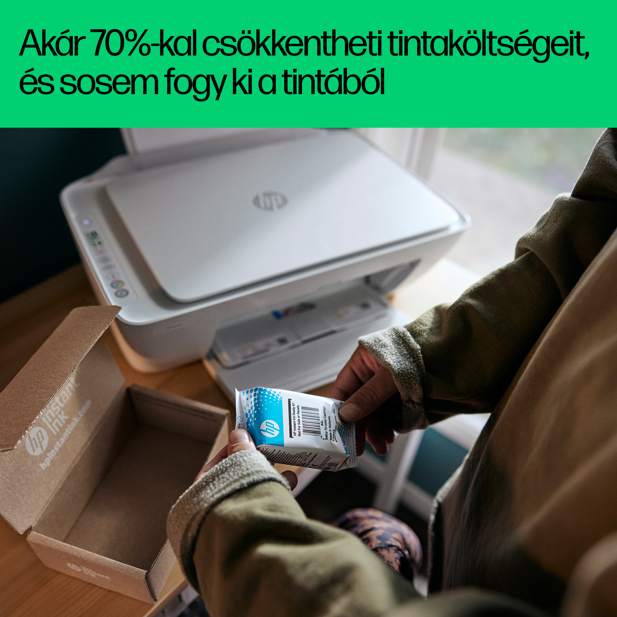 Személy új, kék-fehér HP tintapatront tart egy nyomtató mellett.