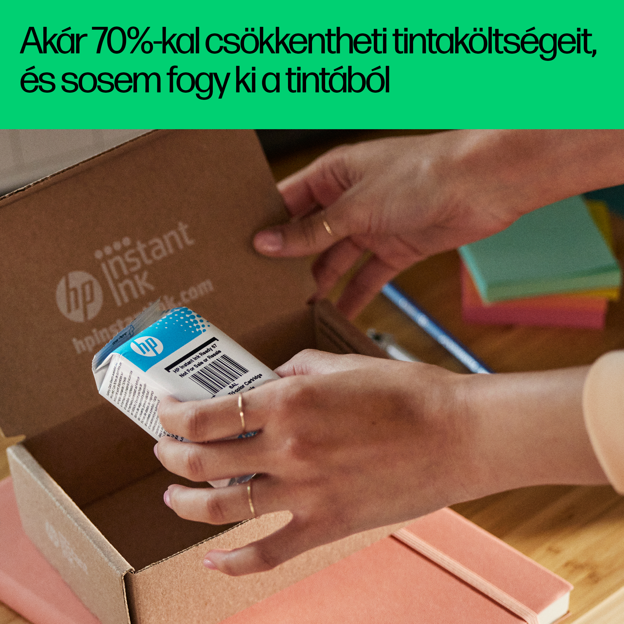Kéz egy kartondobozt nyit, benne HP instant tintapatronnal.