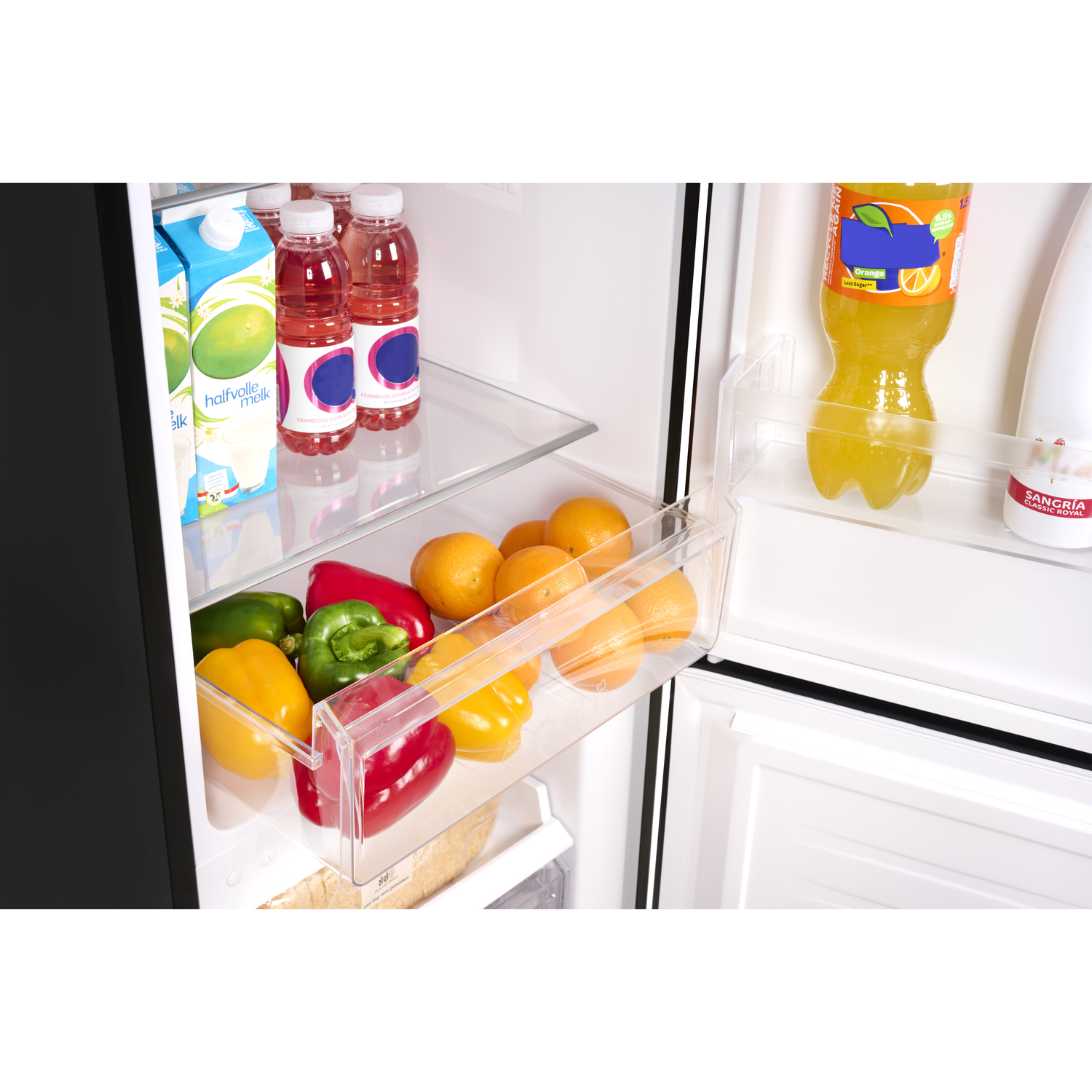 Inside a fridge with shelves full of food. Includes milk, juice, oranges, peppers. Black fridge door visible.
