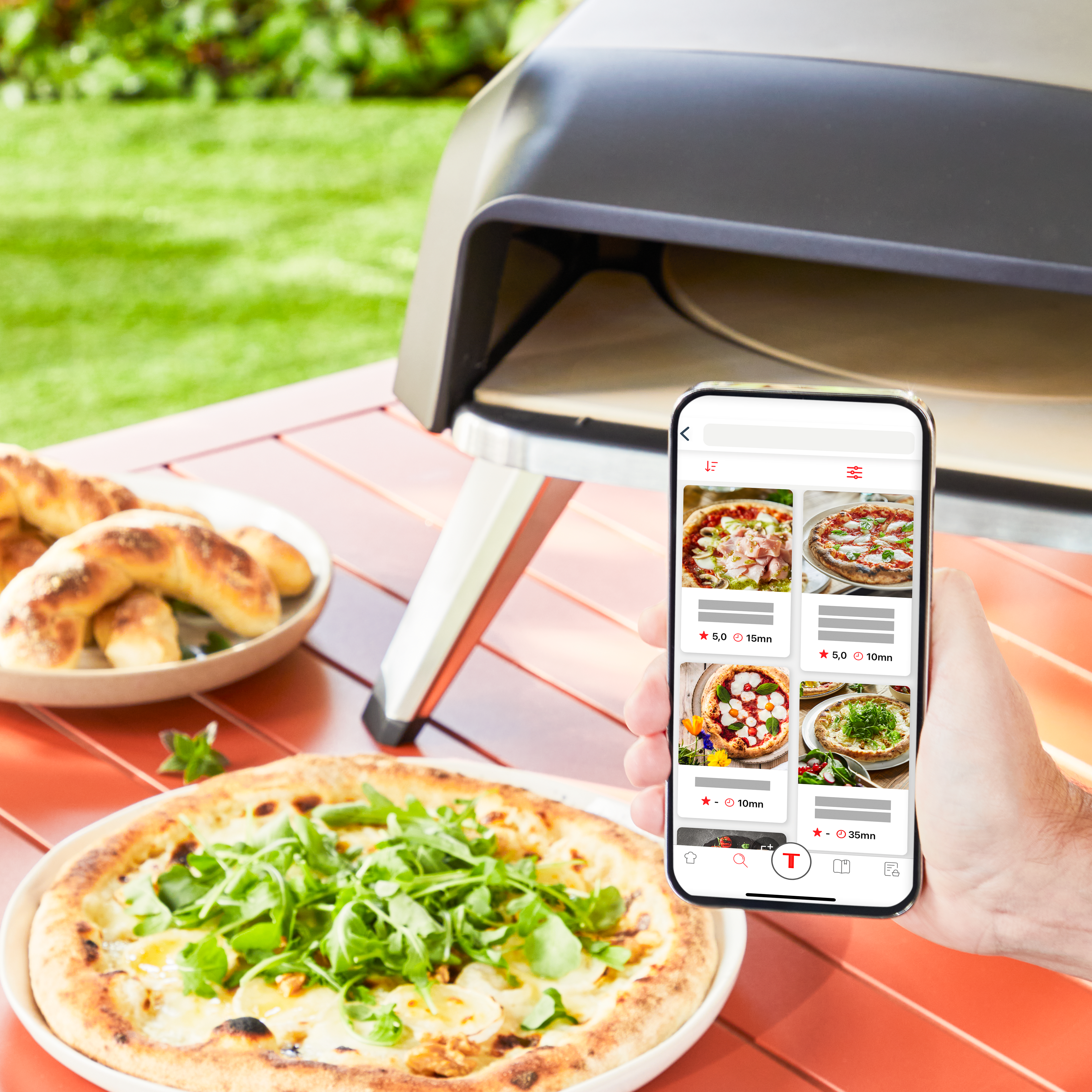 Pizza auf rotem Tisch, Person hält Telefon mit Pizza-Menü. Umgebung im Freien.