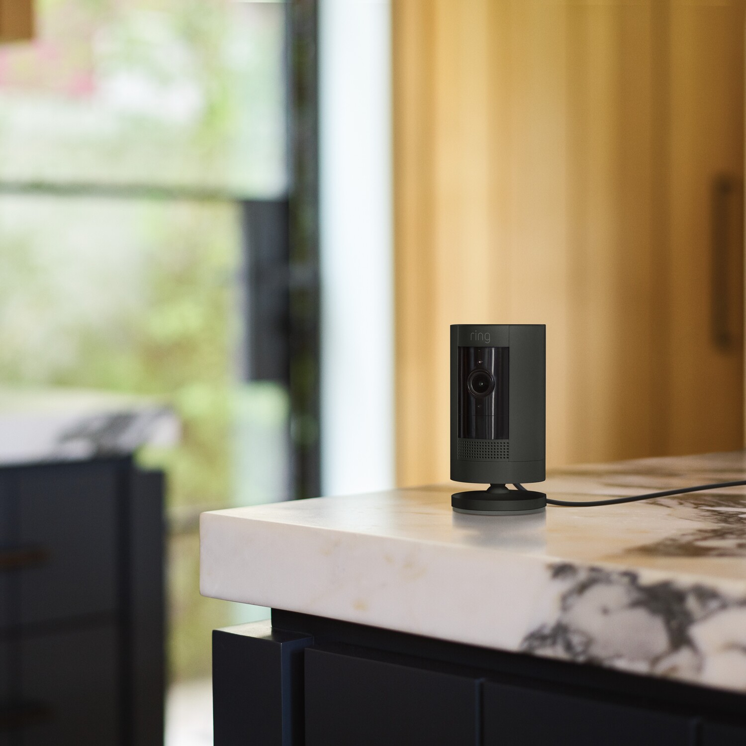 A black Ring security camera on a counter, the background is a kitchen.