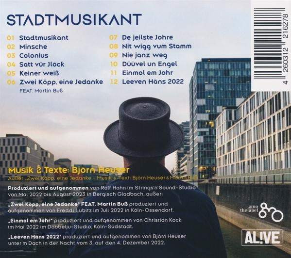 Rückseite eines Mannes mit Hut, der eine Stadtansicht betrachtet, mit deutschem Text über Musik und eine Band.