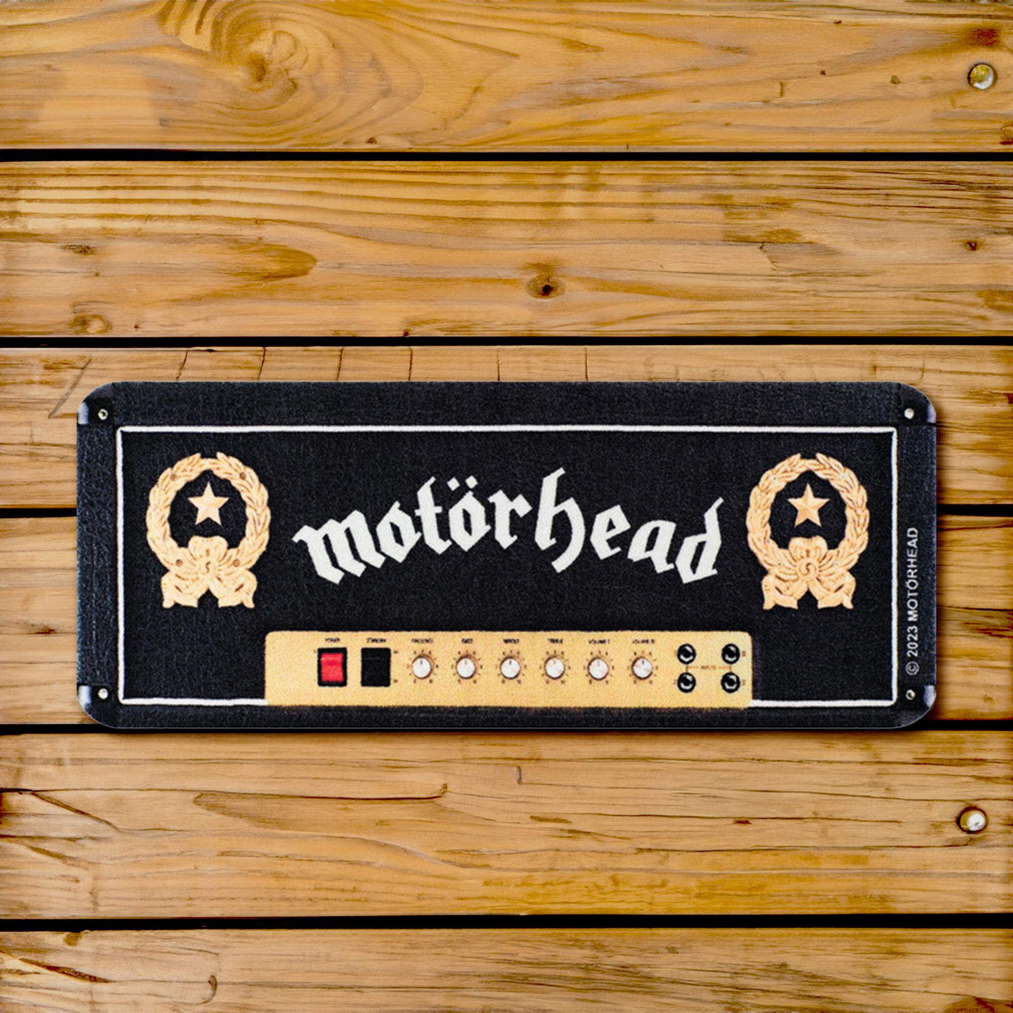 Eine Motörhead-Fußmatte in Form eines Verstärkers auf Holzbohlen.