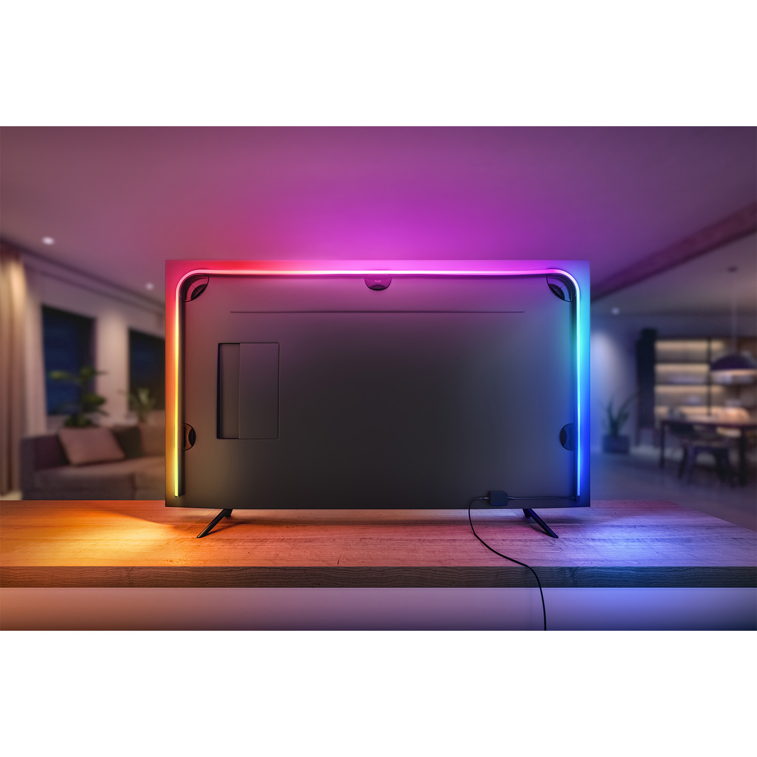 Il retro di una TV nera, con luci colorate lungo i bordi, è appoggiato su un tavolo di legno.