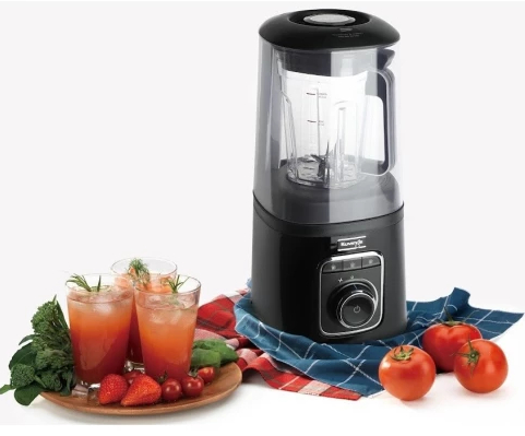 Czarny blender z trzema napojami w szklankach, otoczony pomidorami i truskawkami.