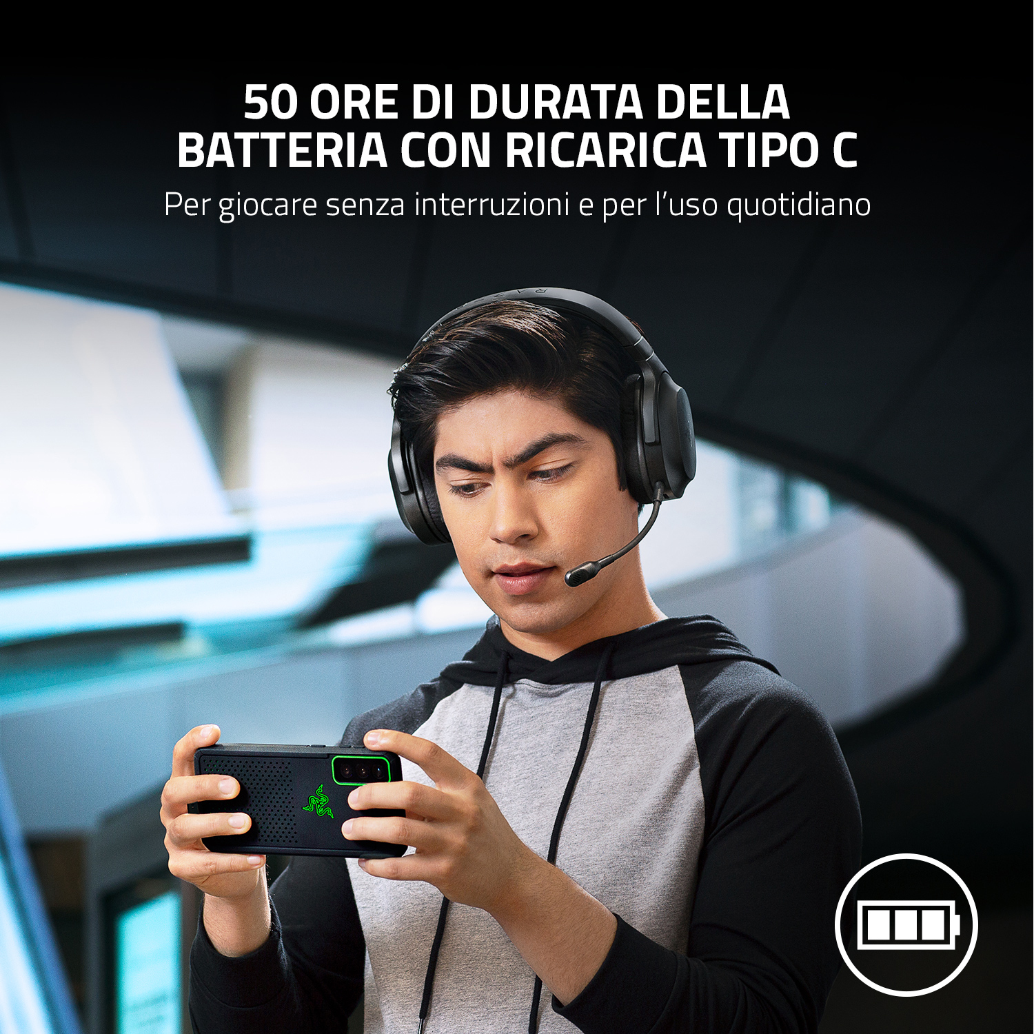 Uomo che gioca su un telefono con cuffie da gioco. Viene visualizzata l'icona della batteria.