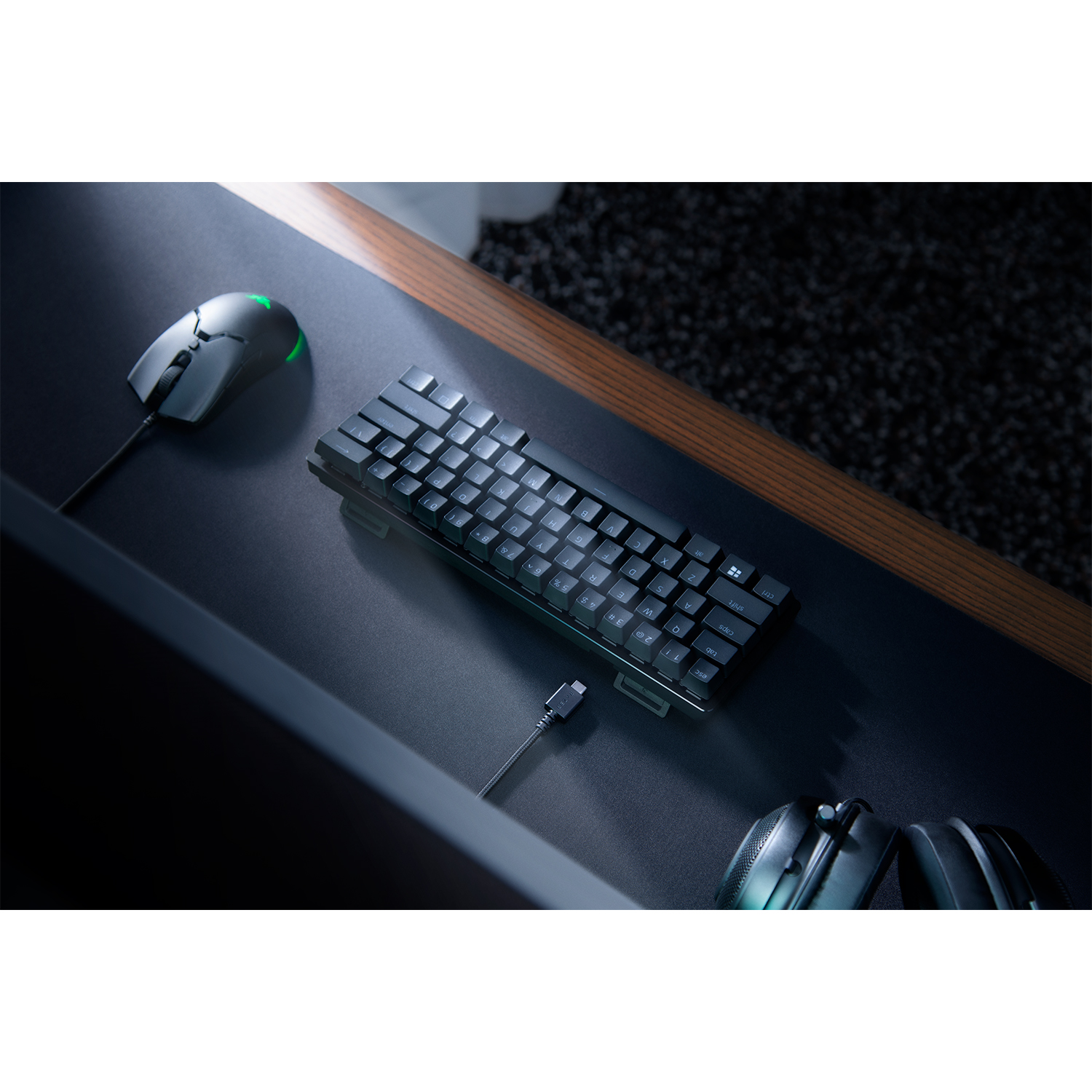 Configurazione di gioco con tastiera, mouse e cuffie su una scrivania. Sfondo scuro.