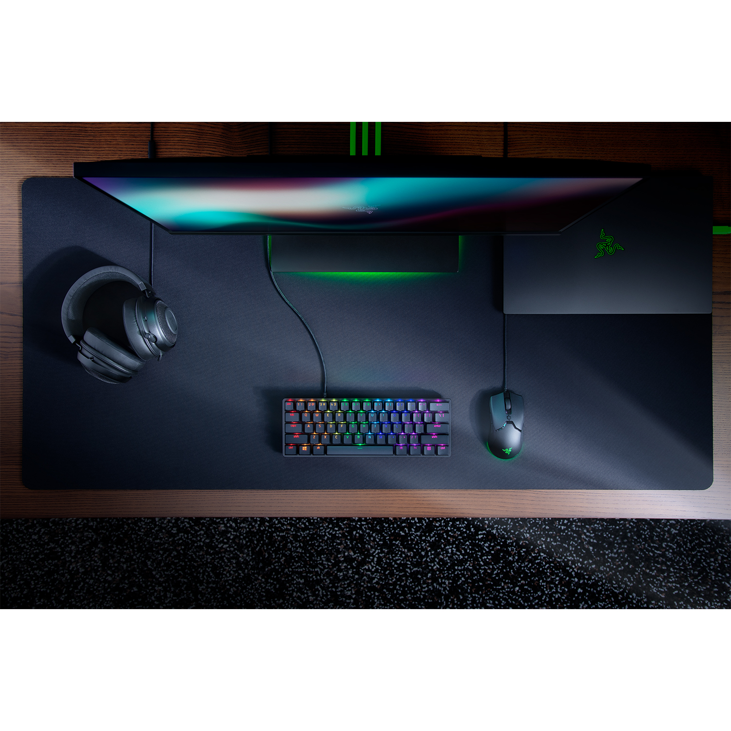 Configurazione di gioco: scrivania nera, monitor, tastiera, mouse e cuffie su un tappetino.