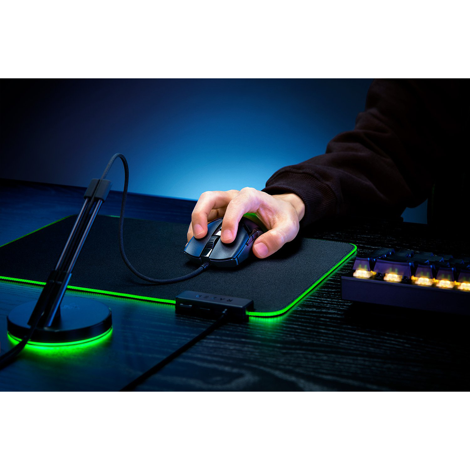 Mano usa mouse su tappetino nero. Tastiera e supporto visibili.
