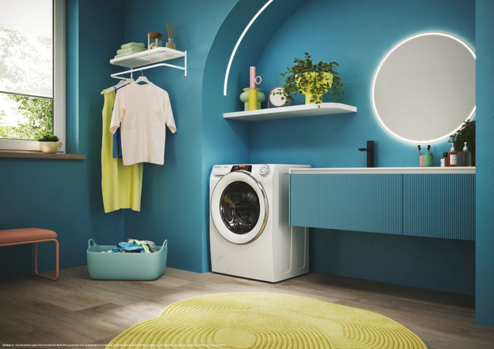 Salle de bain bleue et blanche avec machine à laver, vêtements et miroir rond.