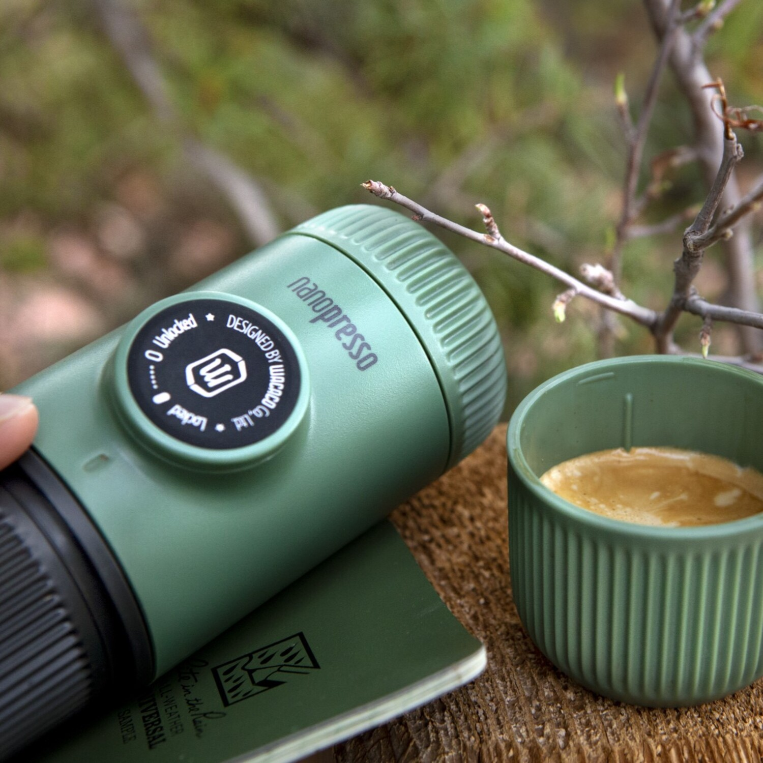 Groene Nanopresso koffiemaker, een kopje koffie en een groen notitieboekje.