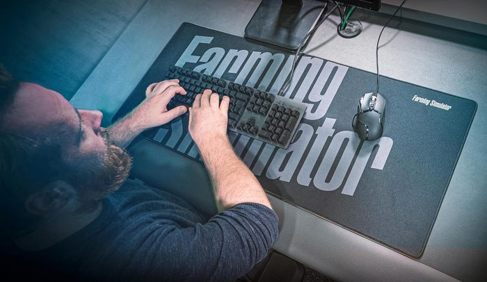 Eine Person tippt auf einer Tastatur mit einer Maus auf einem Mauspapier über einem Schreibtisch.