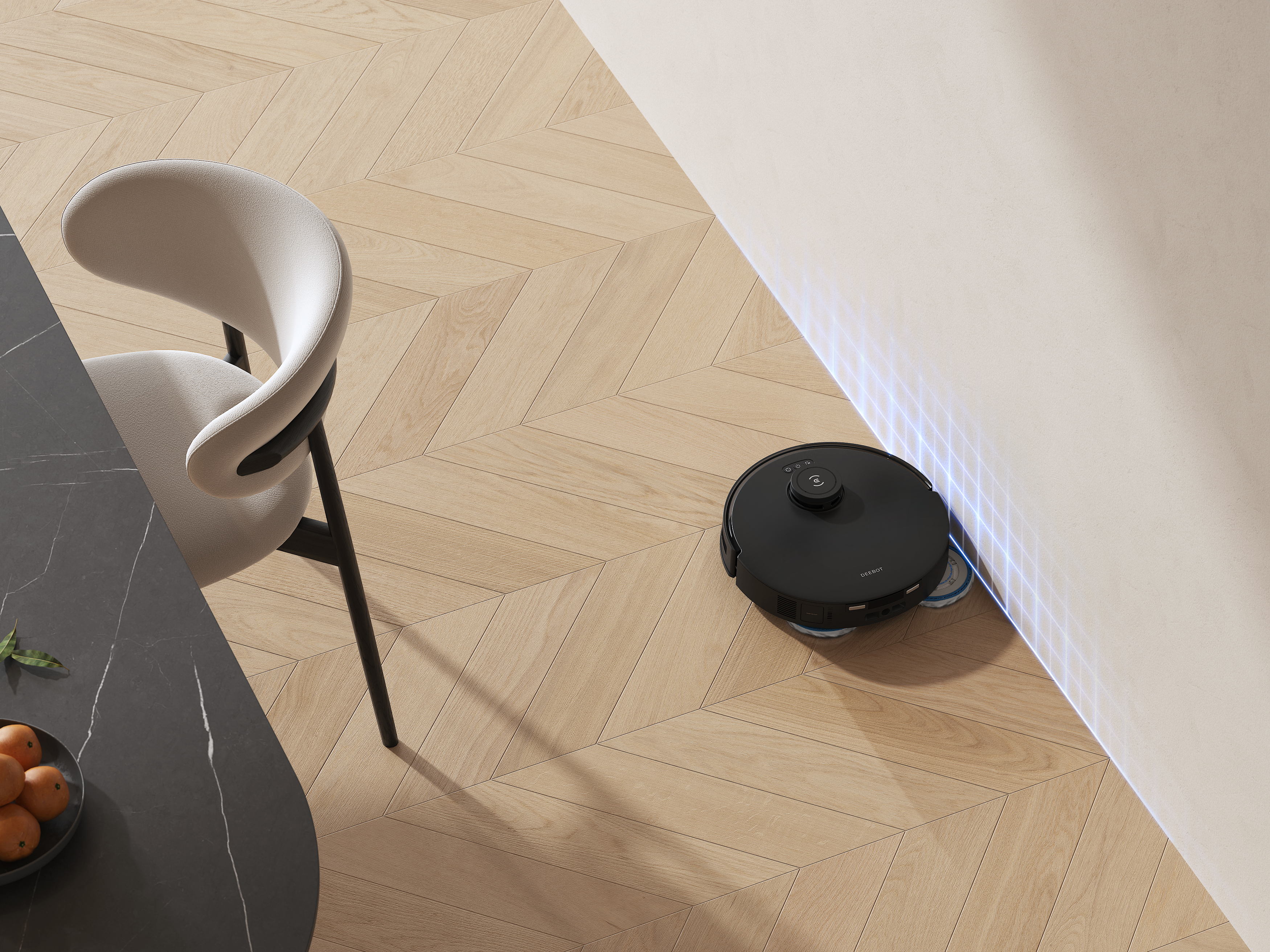 Ein schwarzer Roboter-Staubsauger in der Nähe einer Wand. Der Boden ist helles Holz. Links ein Stuhl.