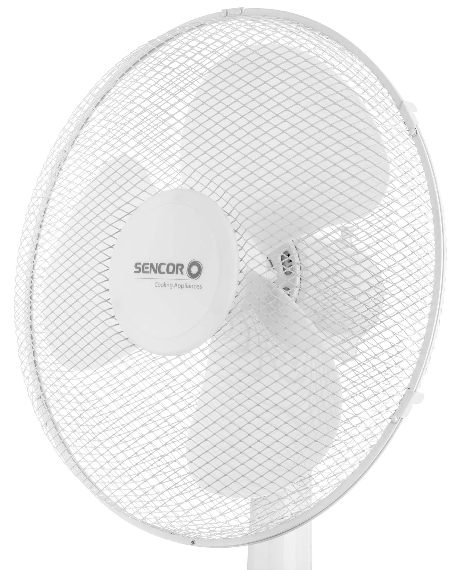 Egy fehér ventilátor védőráccsal a lapátjai felett. A ventilátor egy fehér állványon van.