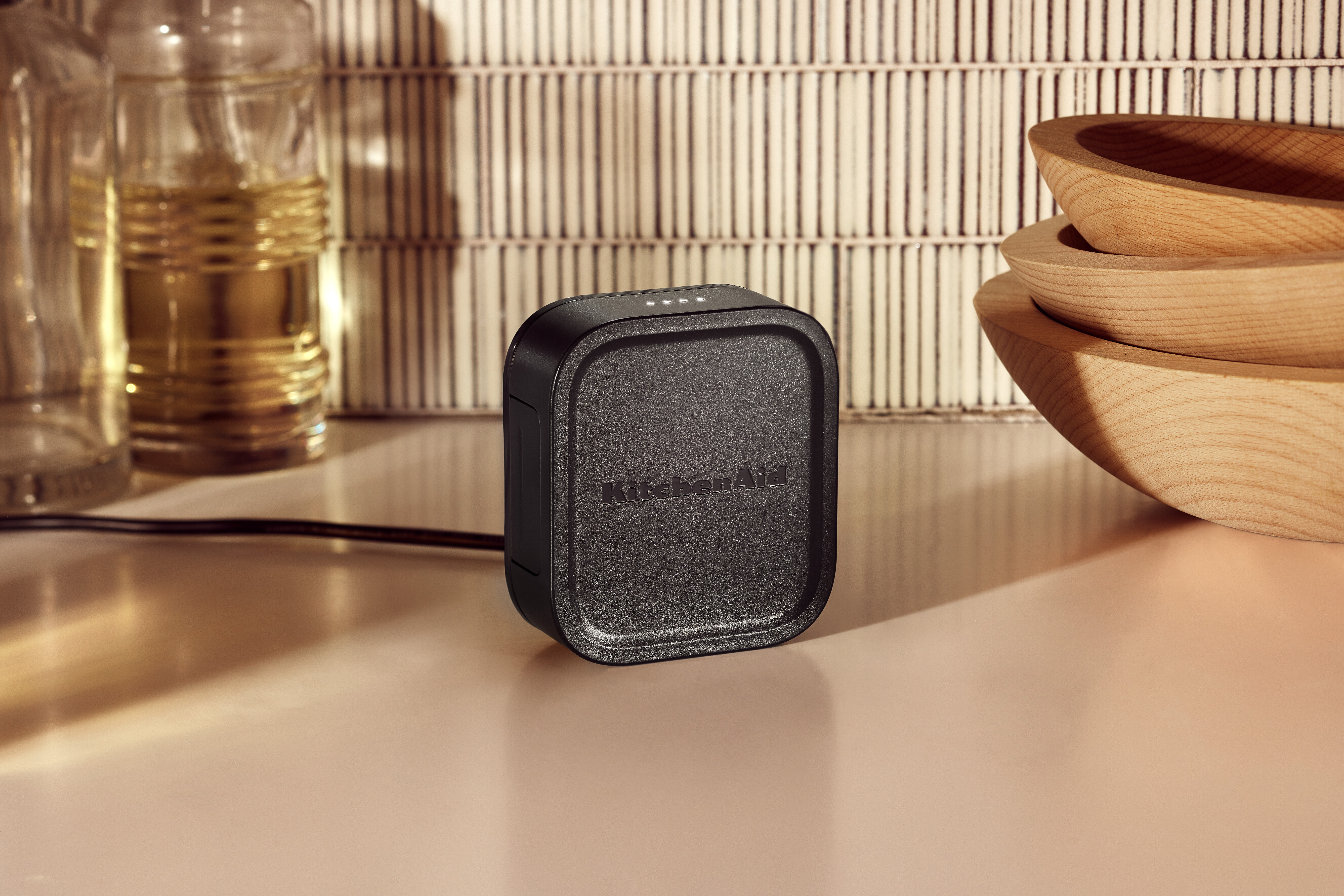 Schwarze KitchenAid Ladestation auf weißer Theke. Gläser und Schalen im Hintergrund.