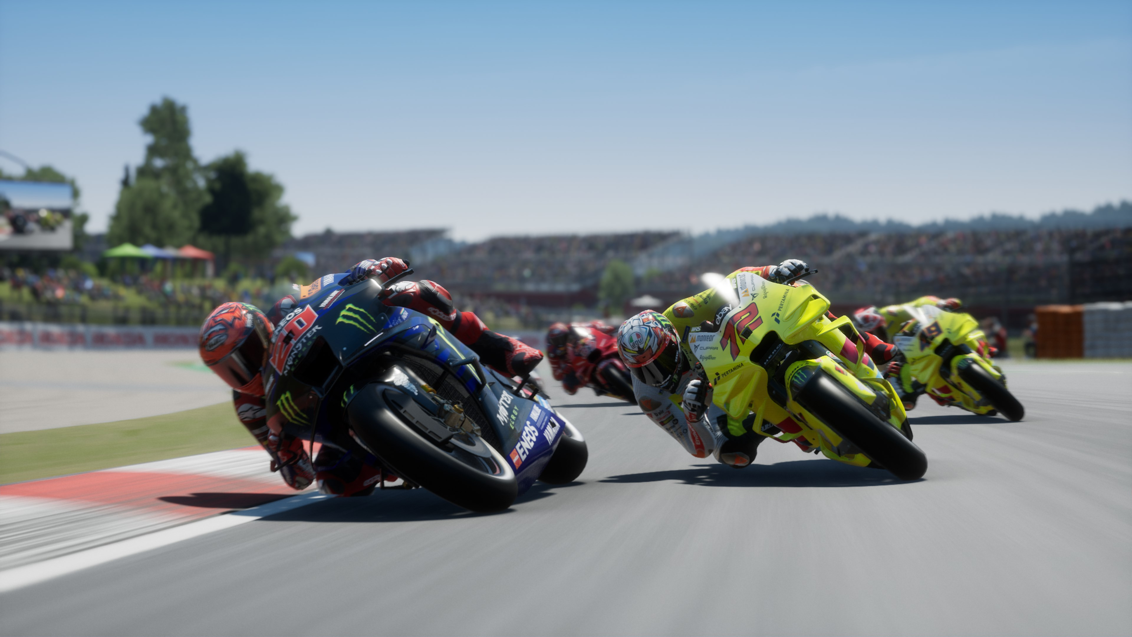 Pilotes de moto en action sur une piste, s'inclinant dans un virage, affichant les couleurs de l'équipe.