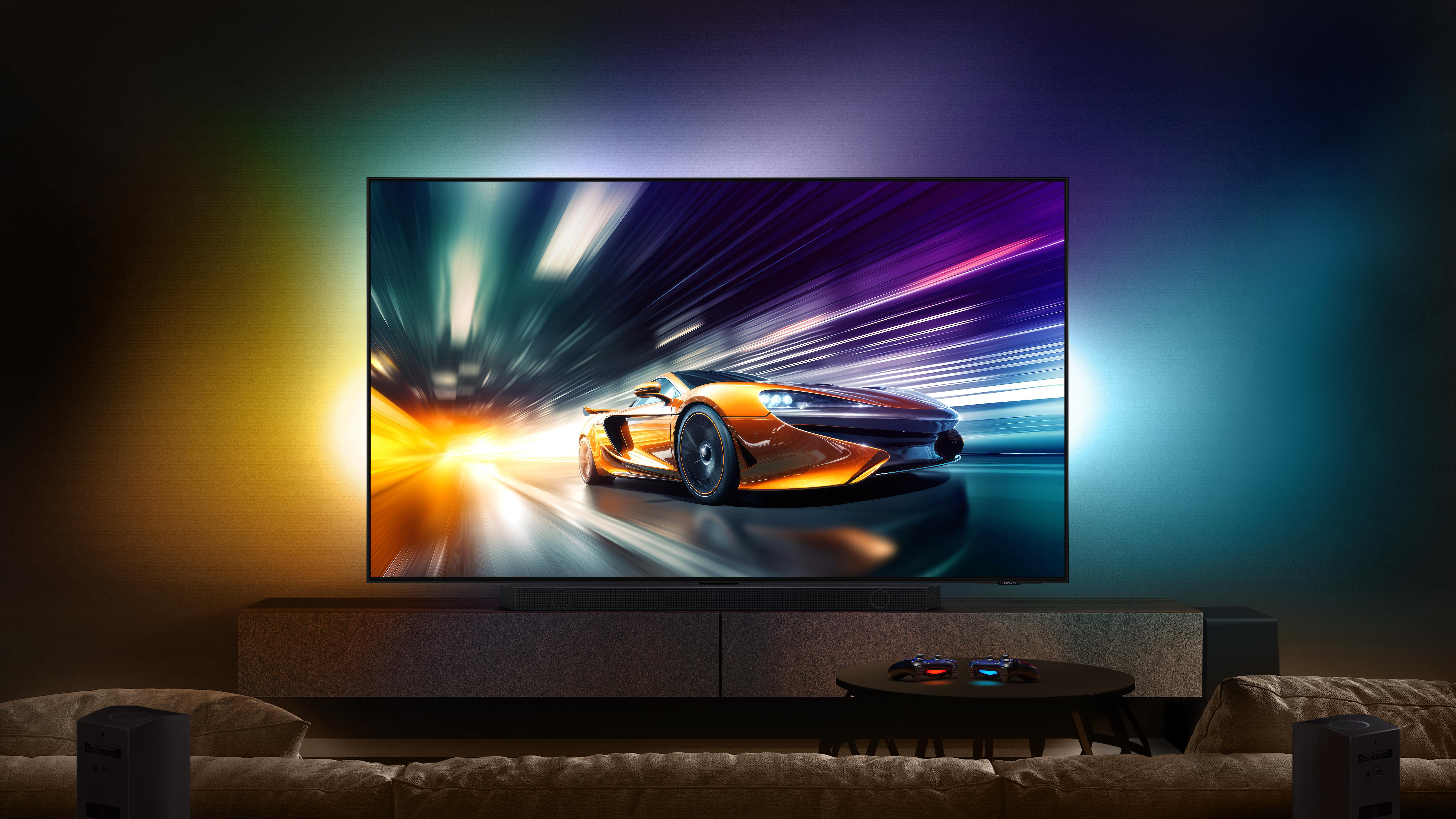 Ein Fernseher mit einer Autorennszene, an der Wand montiert, mit Soundbar und Lautsprechern.