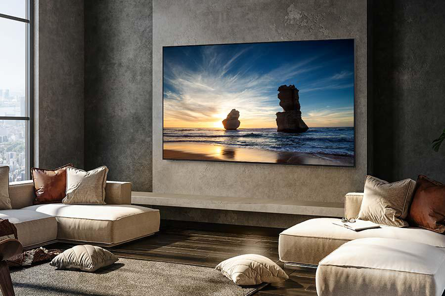 TV-Bildschirm zeigt eine Strandszene. Beige Couch und Kissen. Modernes Wohnzimmer.
