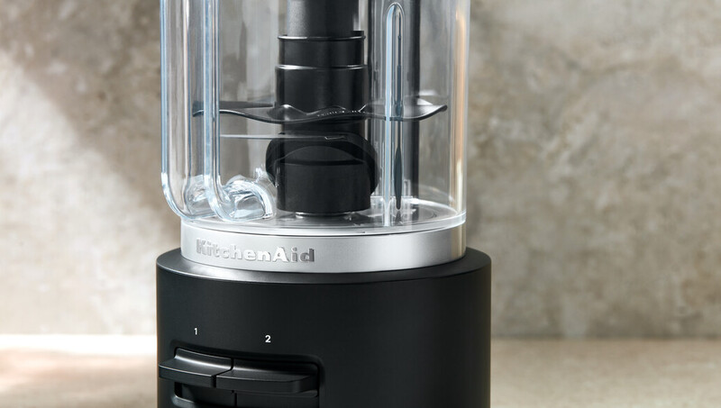 Nahaufnahme eines schwarzen KitchenAid-Foodprozessors. Der Sockel hat Bedienknöpfe und den Markennamen.
