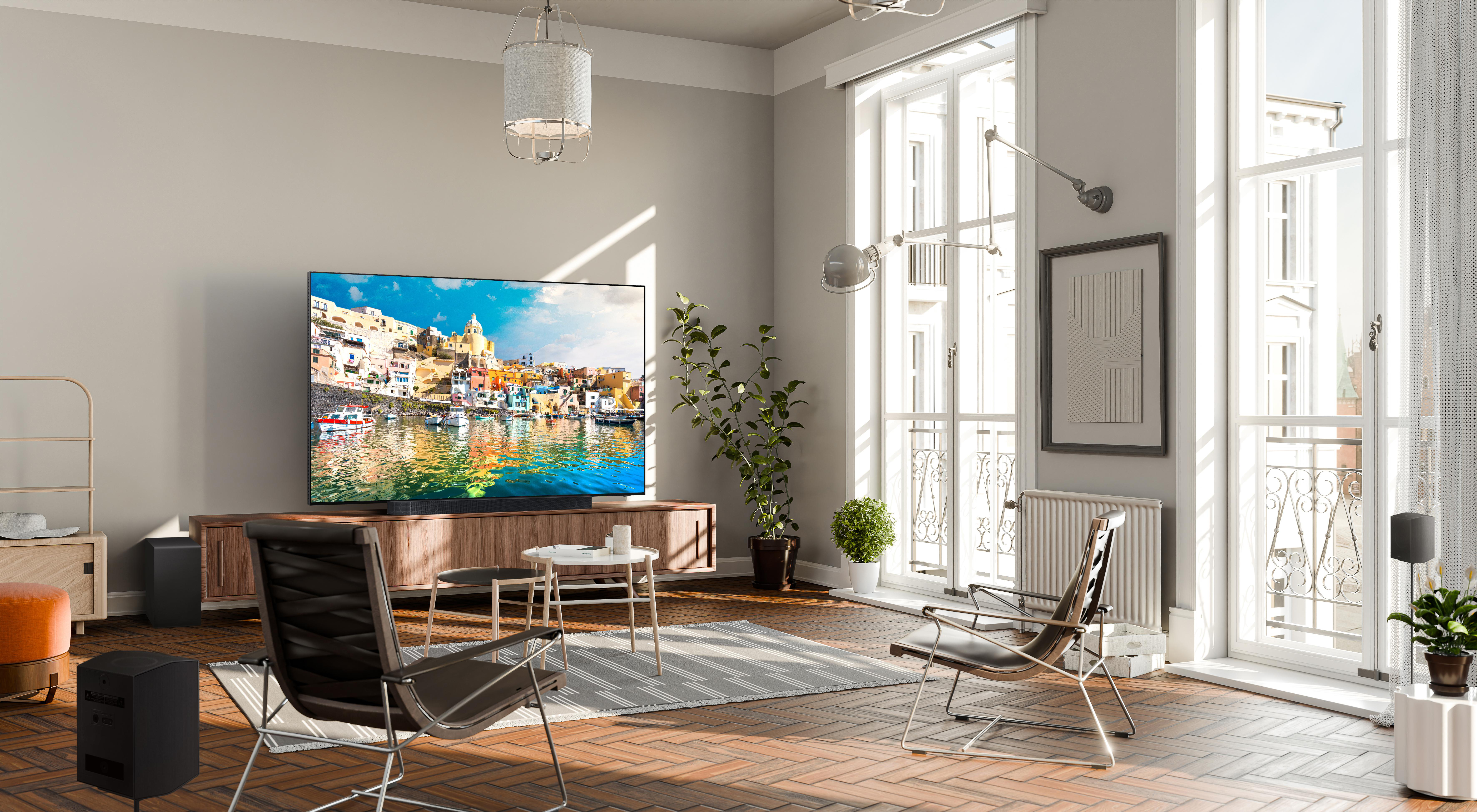 Ein modernes Wohnzimmer mit einem großen Fernseher, Möbeln und großen Fenstern.