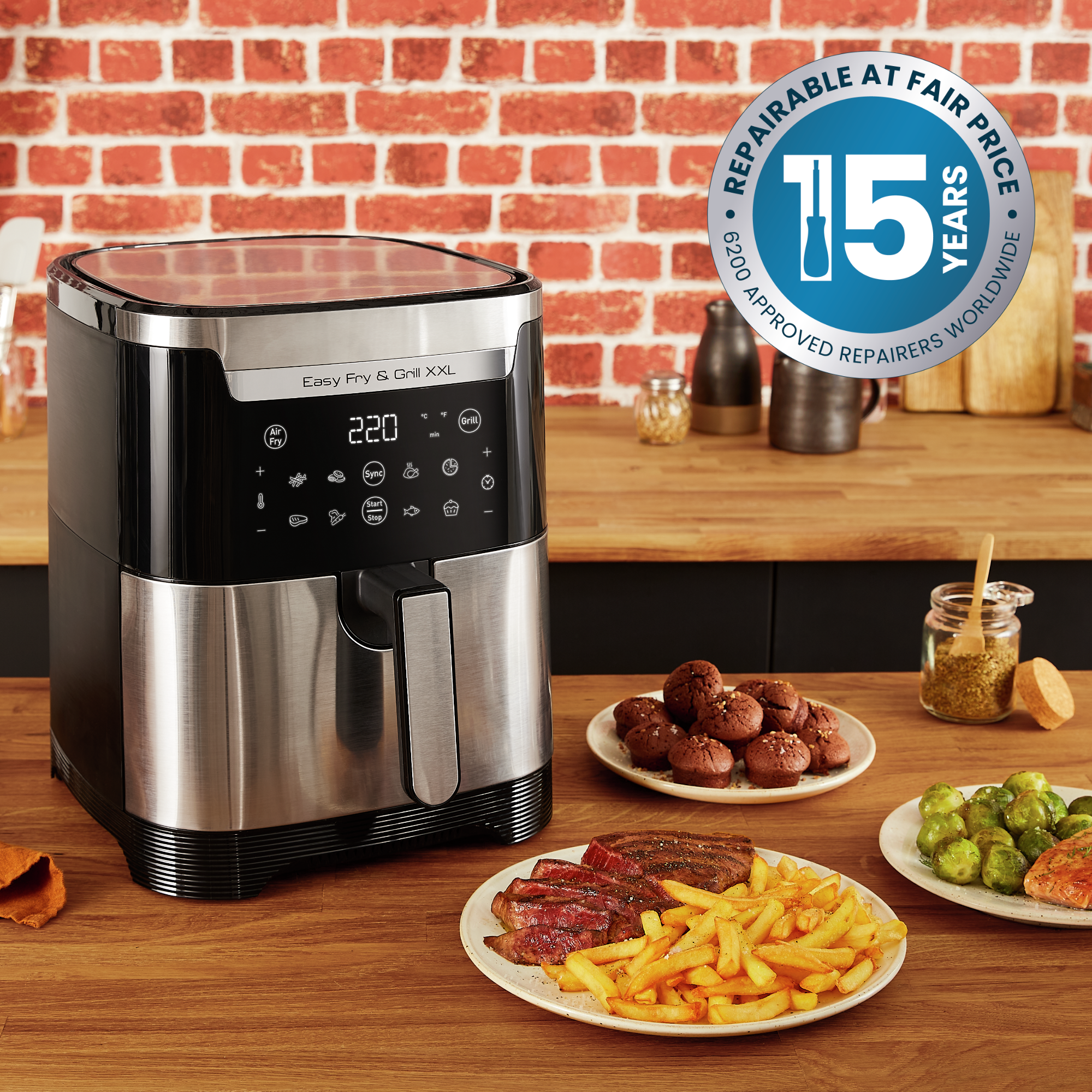 Airfryer met eten, friet, biefstuk en spruitjes, op een houten tafel.