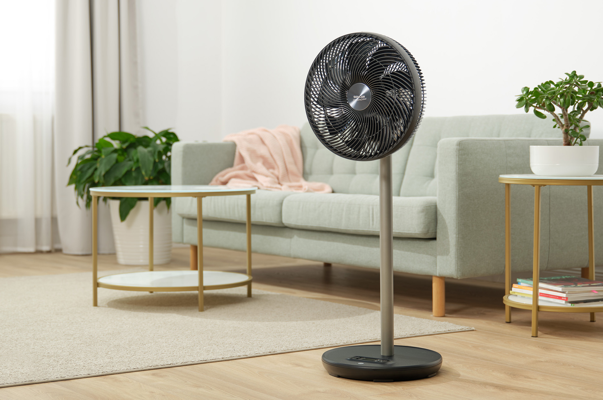 Modern nappali álló ventilátorral, kanapéval, növényekkel és dekorációval. Lágy világítás.