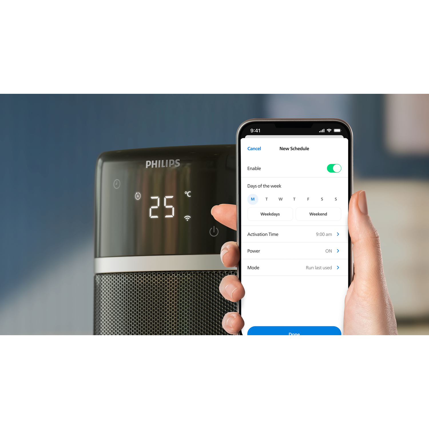 A hand holding a phone, setting a new schedule for a Philips heater. Heater is in the background.