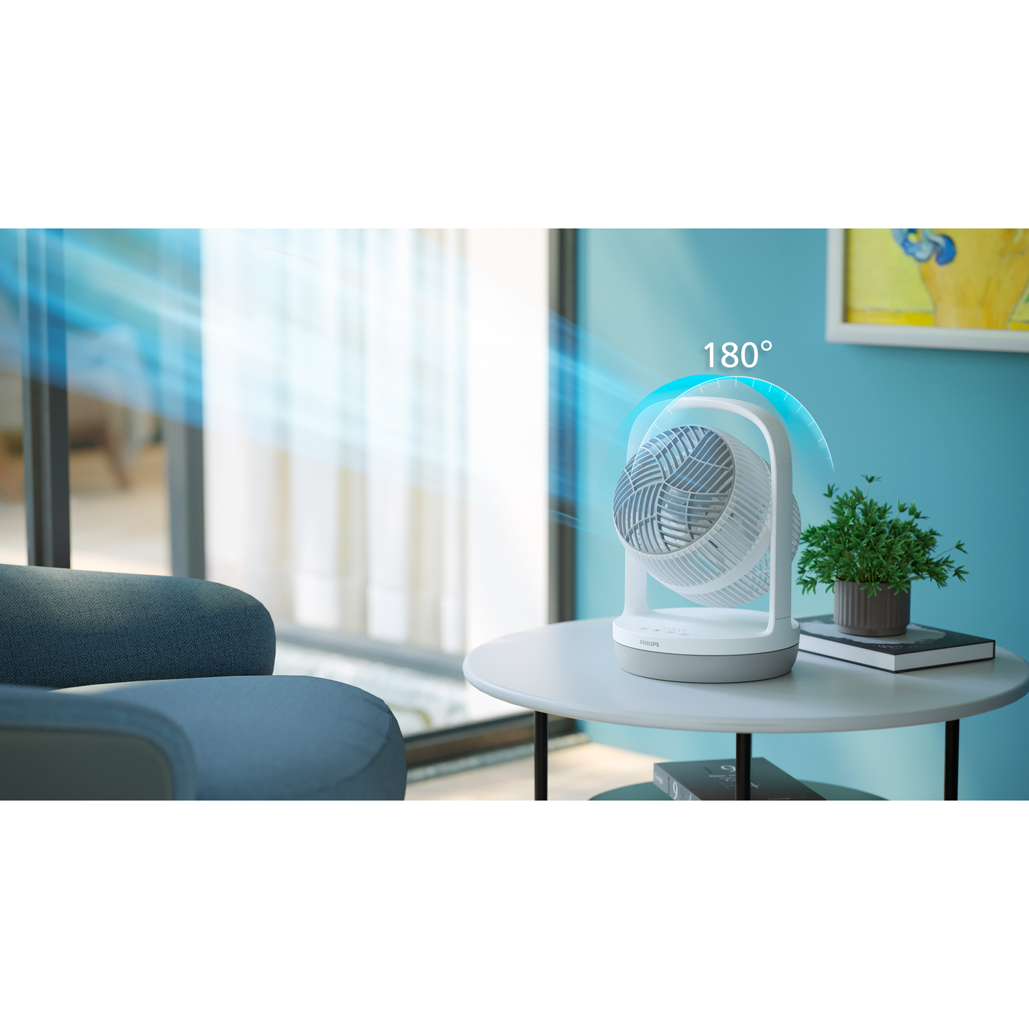 Witte ventilator op tafel, blauwe luchtstroom, met een kleine plant en een raam op de achtergrond.