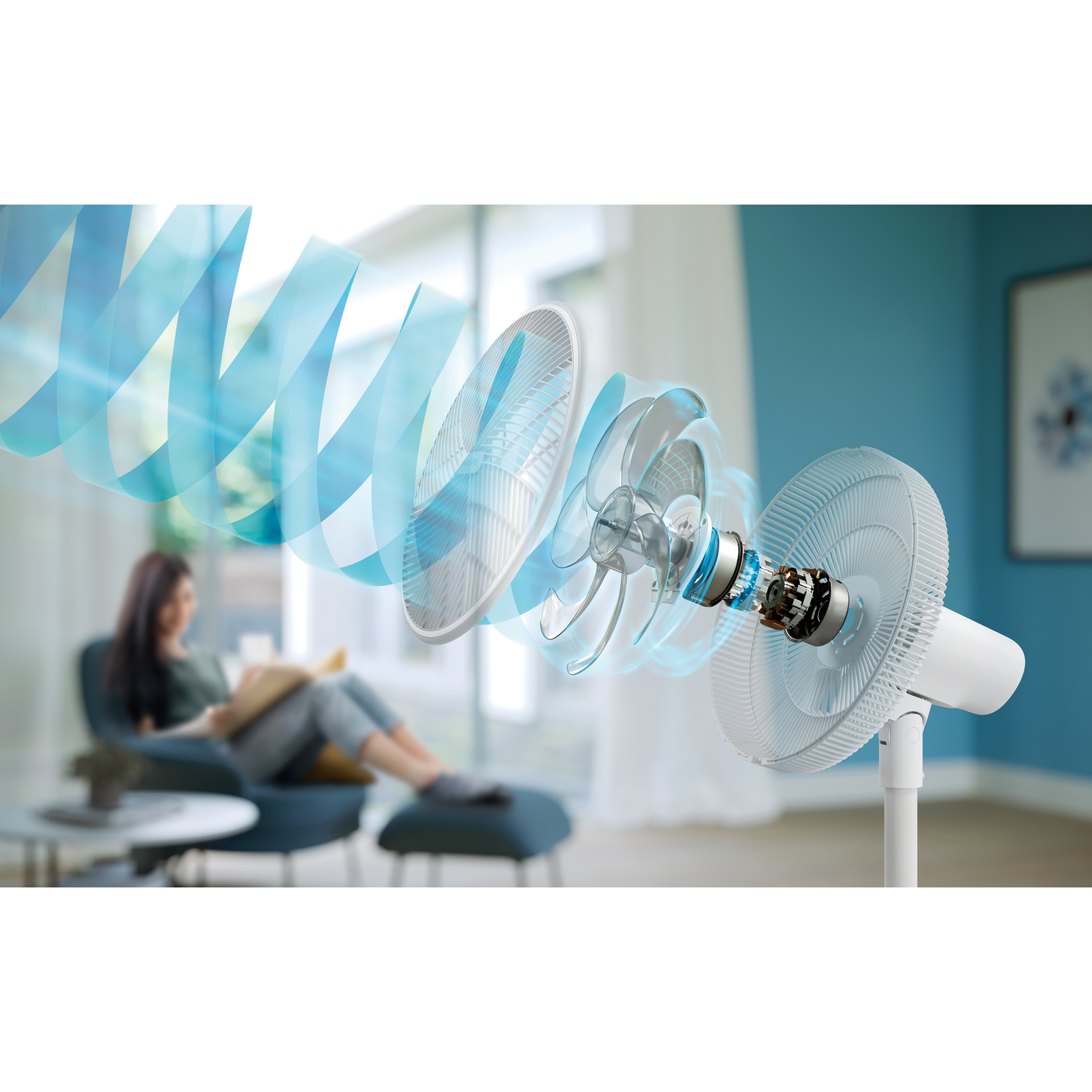 Fan's interior parts are visible. A woman reading in background, blue and white color scheme.