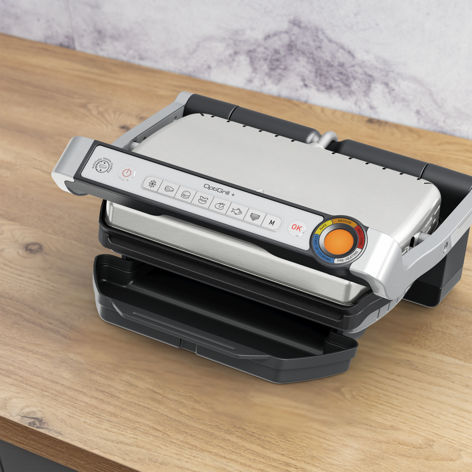 Een zilveren en zwarte OptiGrill+ staat op een houten oppervlak. Hij is open en klaar voor gebruik.