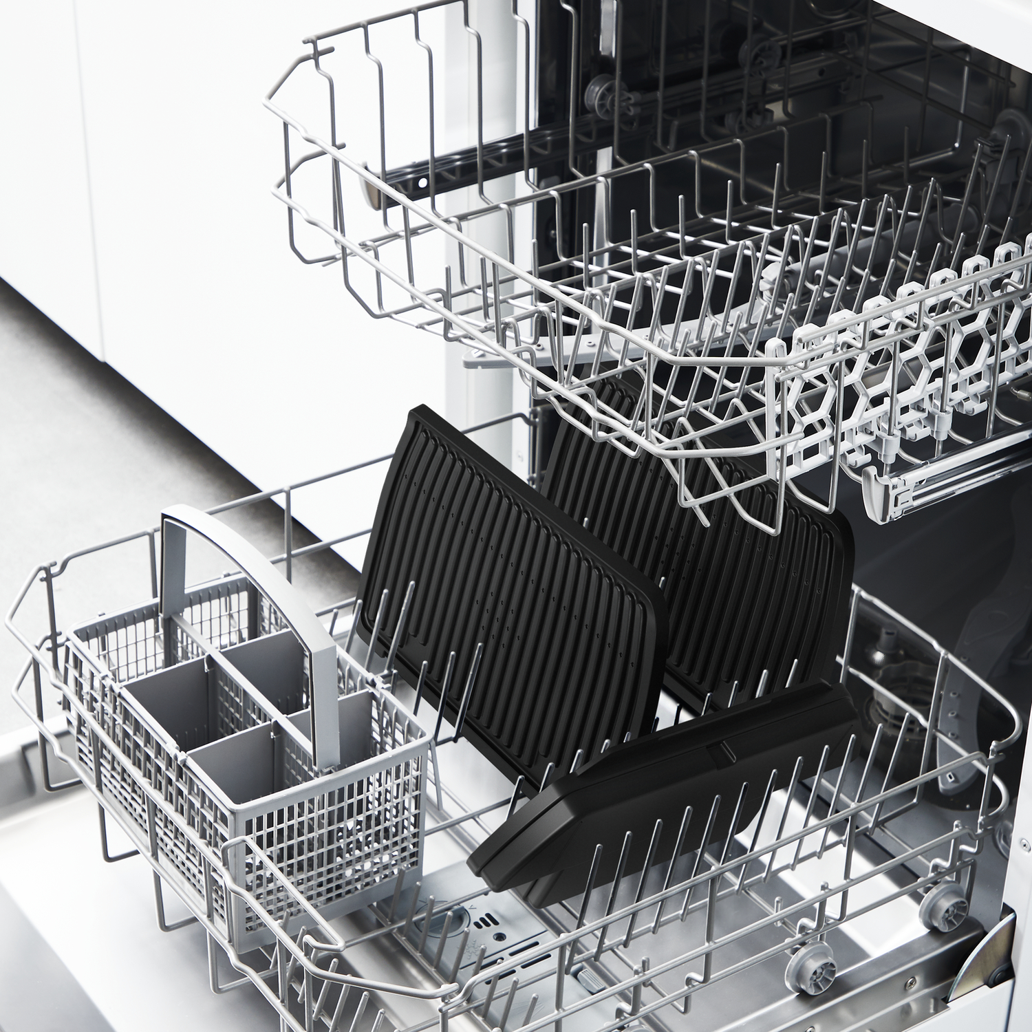 Dishwasher with black grill plates inside. The plates are placed on the rack.