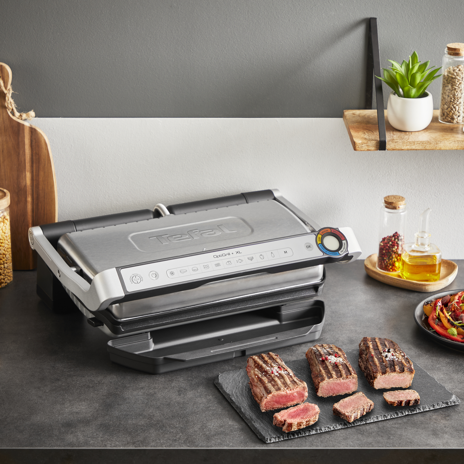 Grill with steaks, wooden board, shelf with plant, and other ingredients.