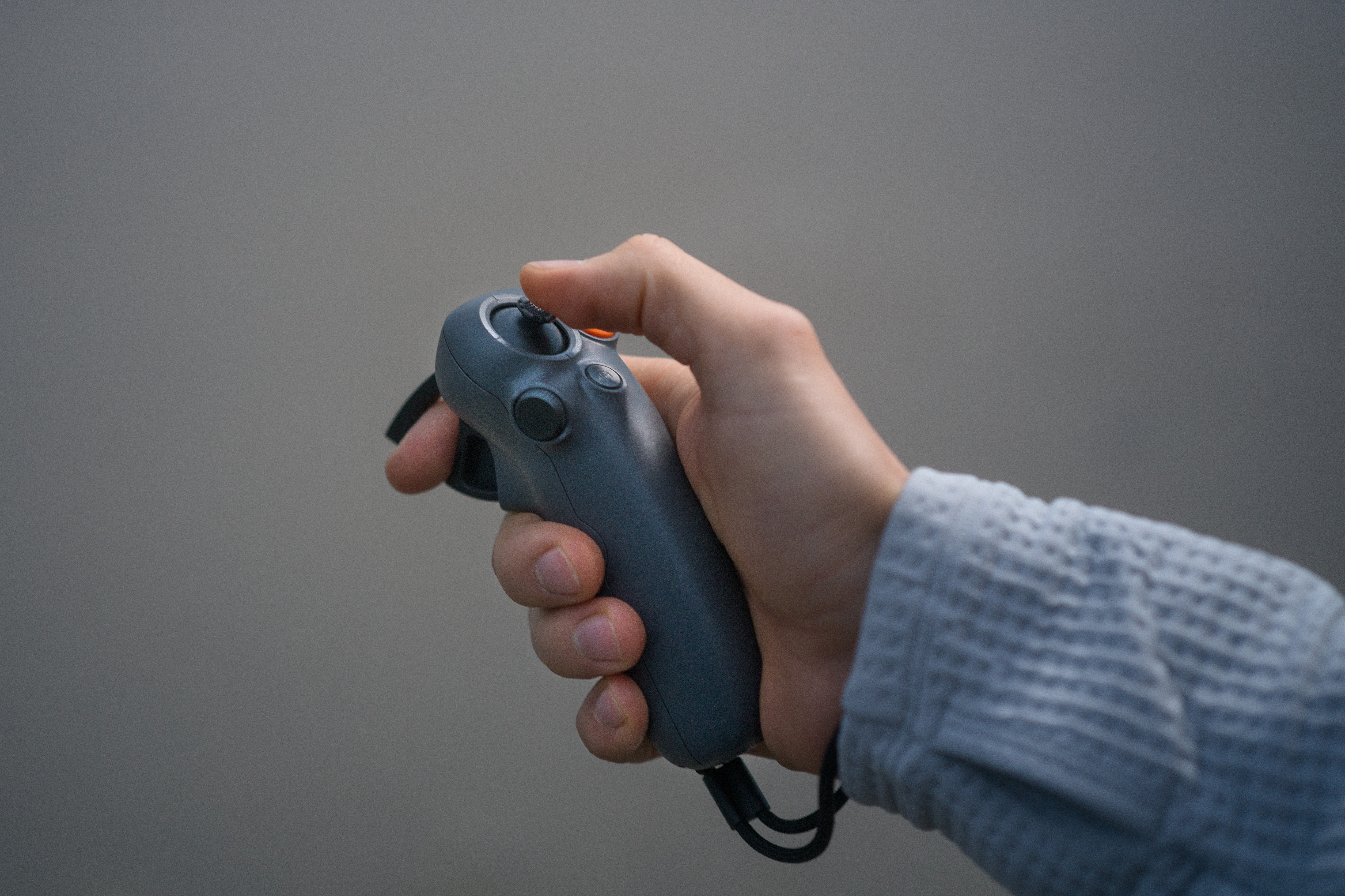 Main tenant une manette VR grise. Un doigt appuie sur un bouton.