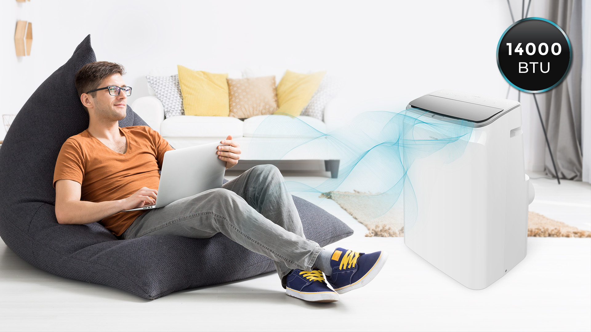Un hombre usa una laptop en un sillón. Un aire acondicionado blanco está junto a él con aire azul fluyendo.