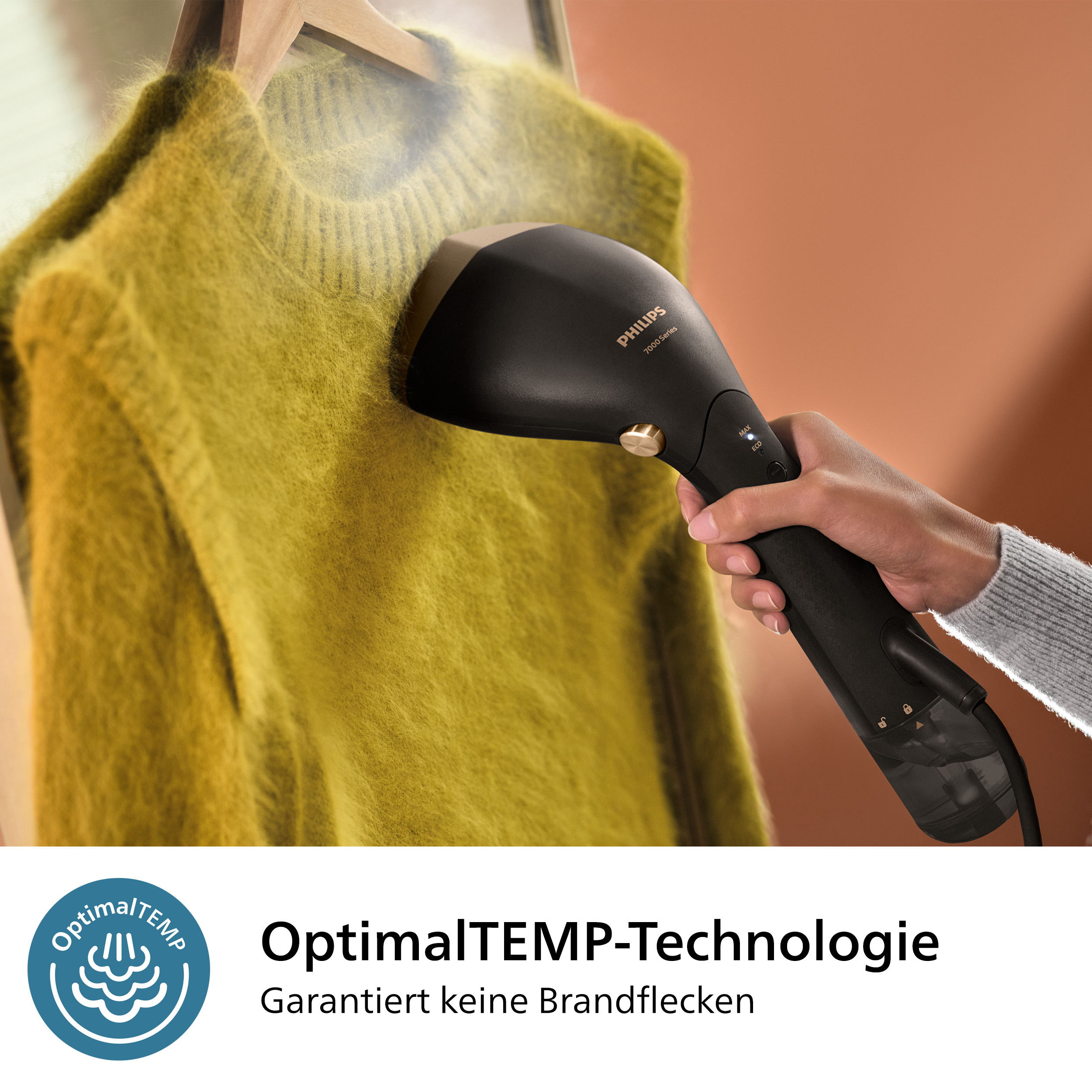 Ein schwarzer Philips-Dampfer, der einen gelben Pullover auf einem Holzkleiderbügel dämpft. Hand hält Dampfer.