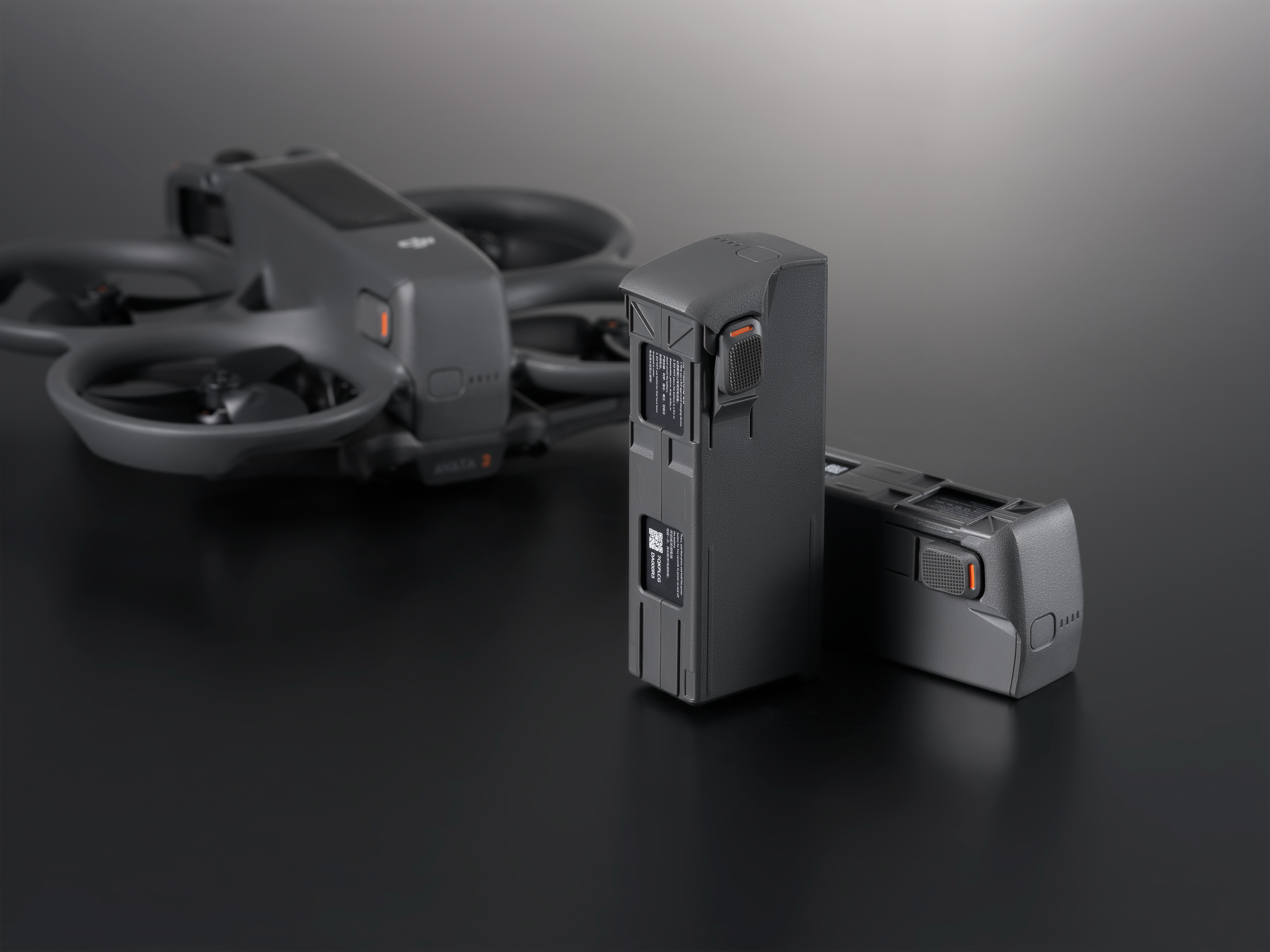 Deux batteries de drone et un drone. Surface sombre.