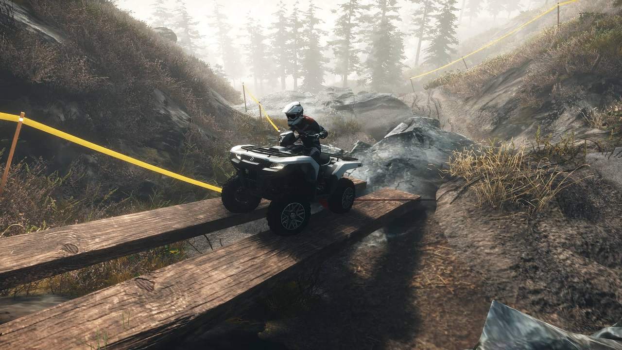 Une personne chevauchant un quad sur un pont en bois au-dessus d'un ruisseau.