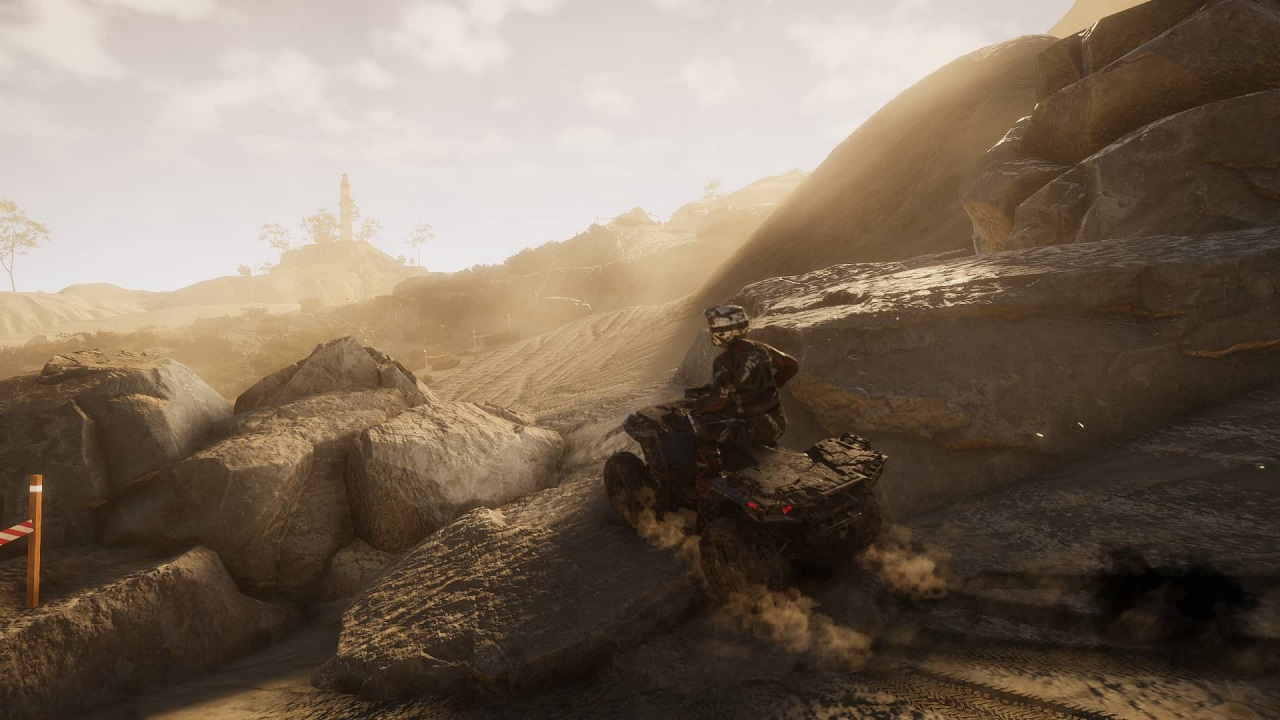 Une personne sur un quad sur une piste de terre. Environnement poussiéreux avec terrain rocheux et ciel clair.