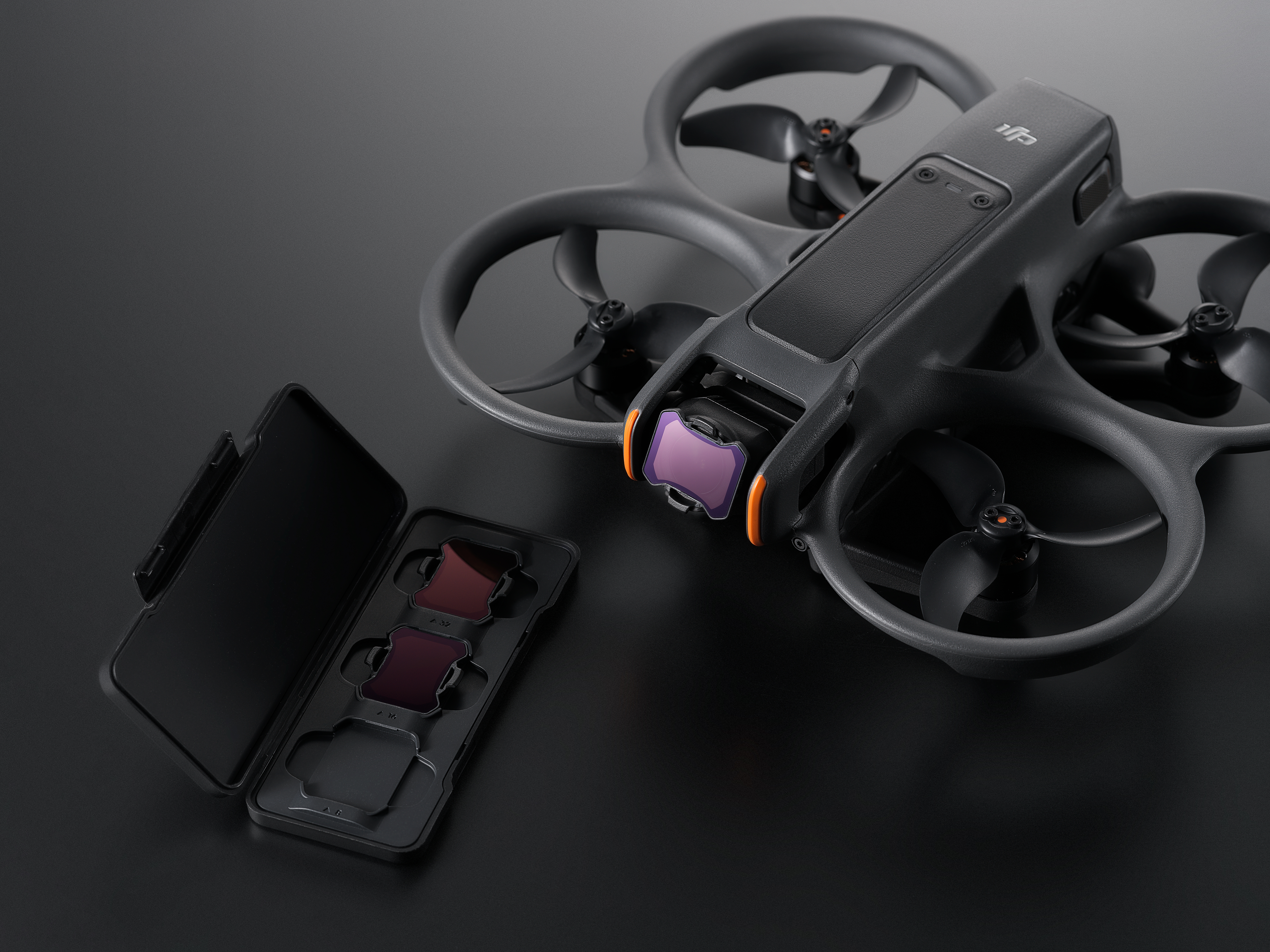 Un drone con una fotocamera e un set di filtri in una custodia, su una superficie scura. Vista da vicino.