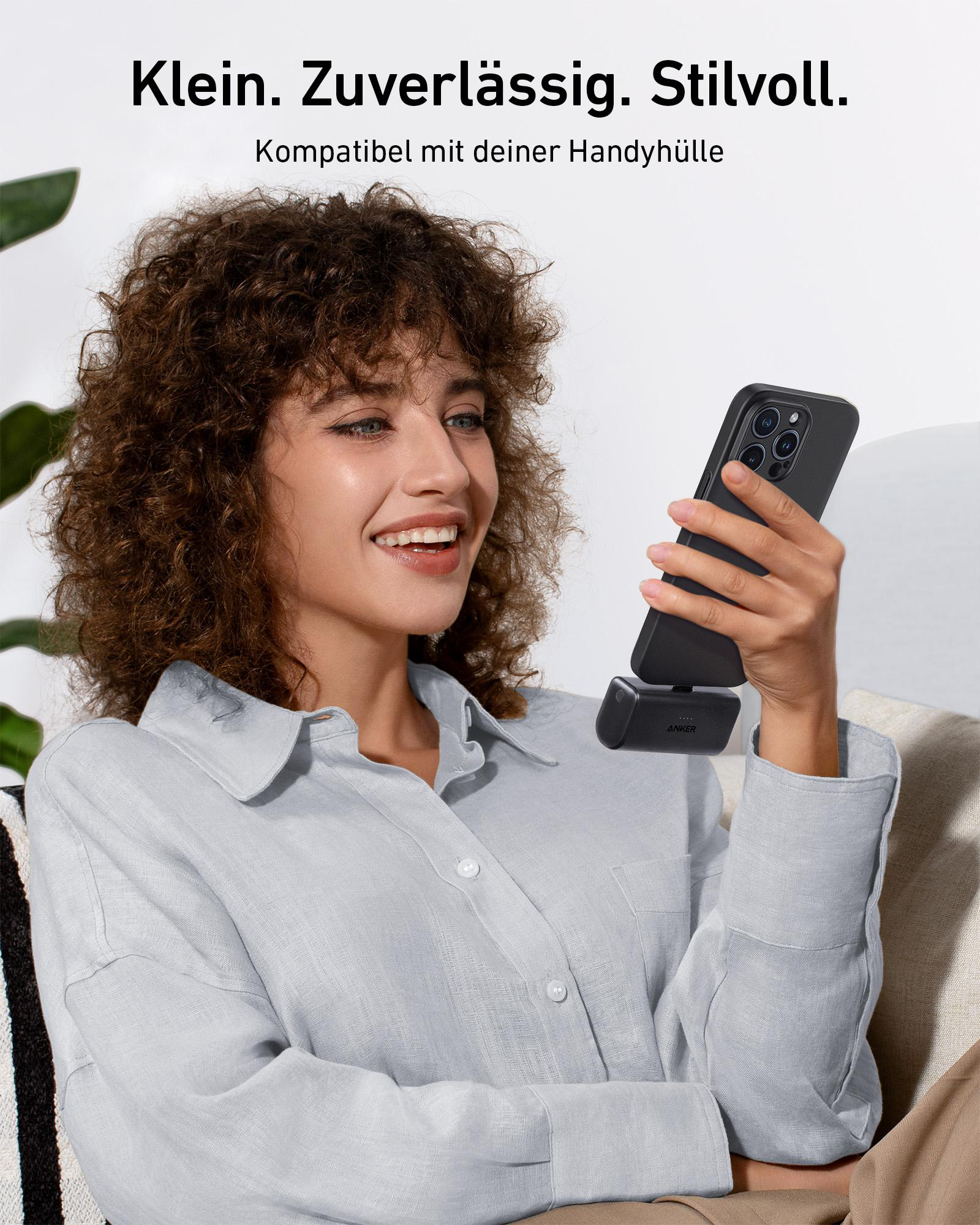 Eine Frau hält ein Telefon mit angeschlossener Powerbank. Text: Klein. Zuverlässig. Stilvoll.
