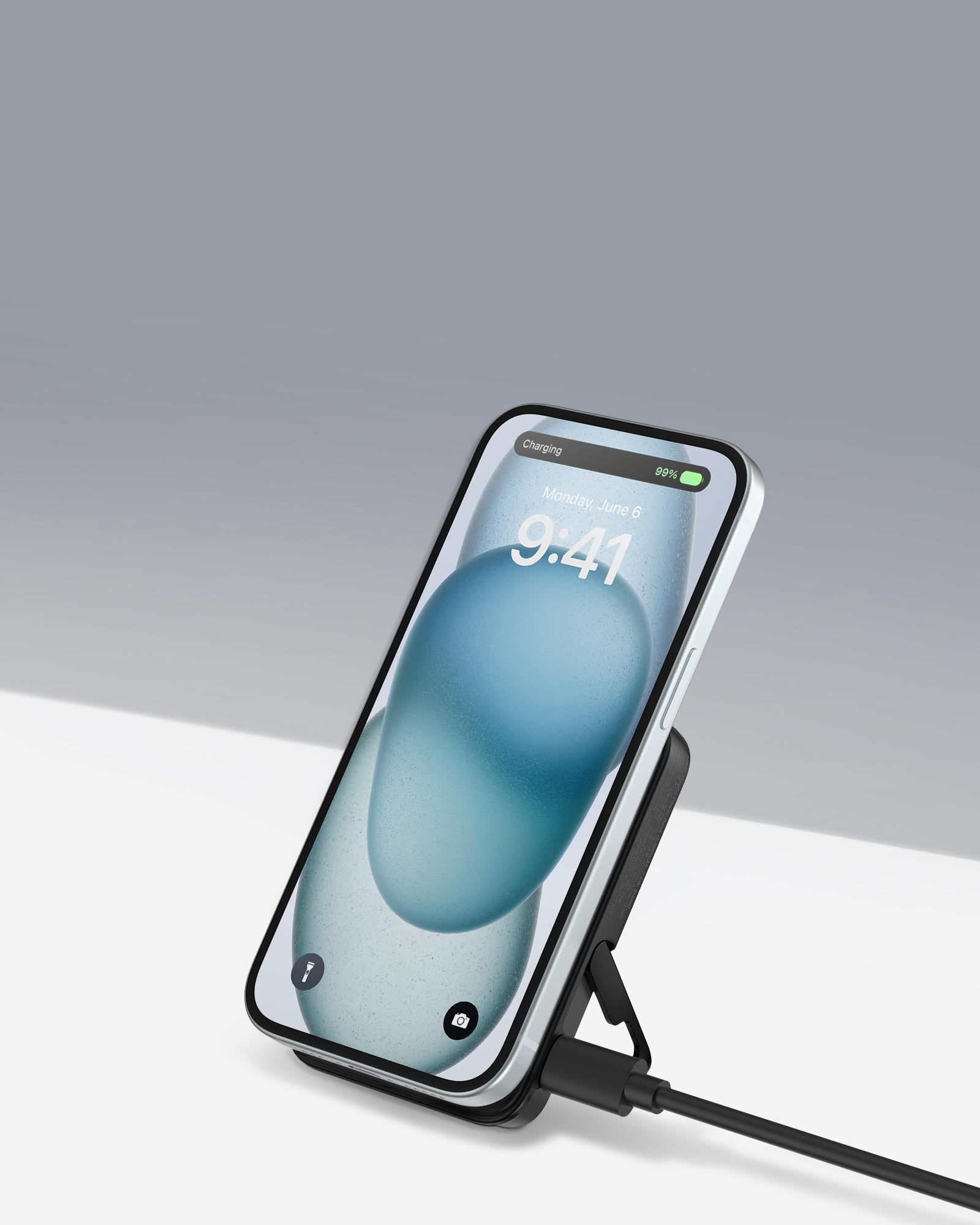 Ein Smartphone auf einem kabellosen Ladeständer, mit einem Ladekabel auf weißer Oberfläche.