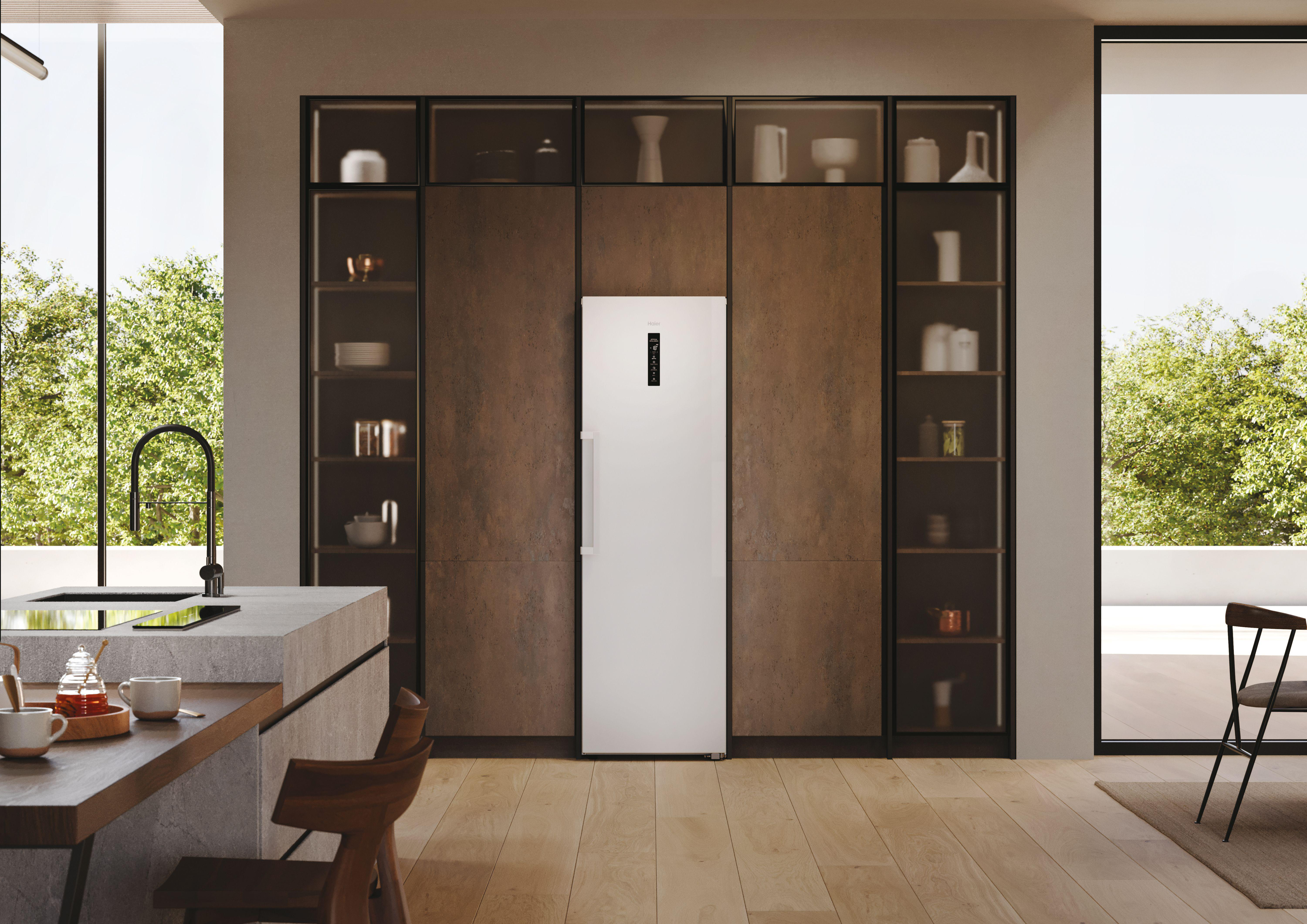 Ein weißer Kühlschrank steht in einer modernen Küche mit dunklen Schränken und Dekor.