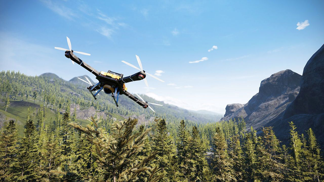 Eine Drohne fliegt über einen Wald und Berge unter blauem Himmel. Die Drohne ist gelb und schwarz.